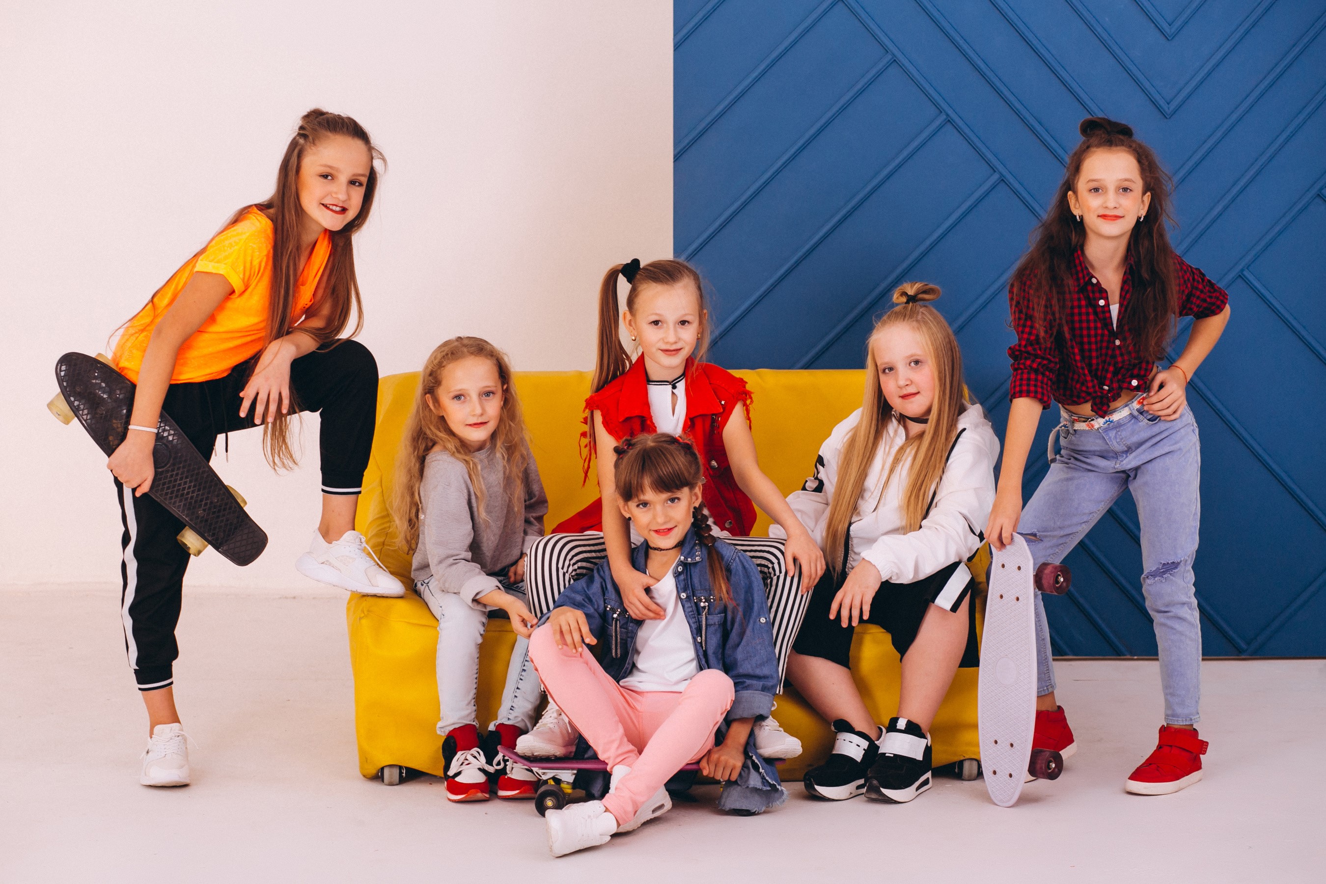 Six girls with skateboards on a yellow couch HD Wallpaper