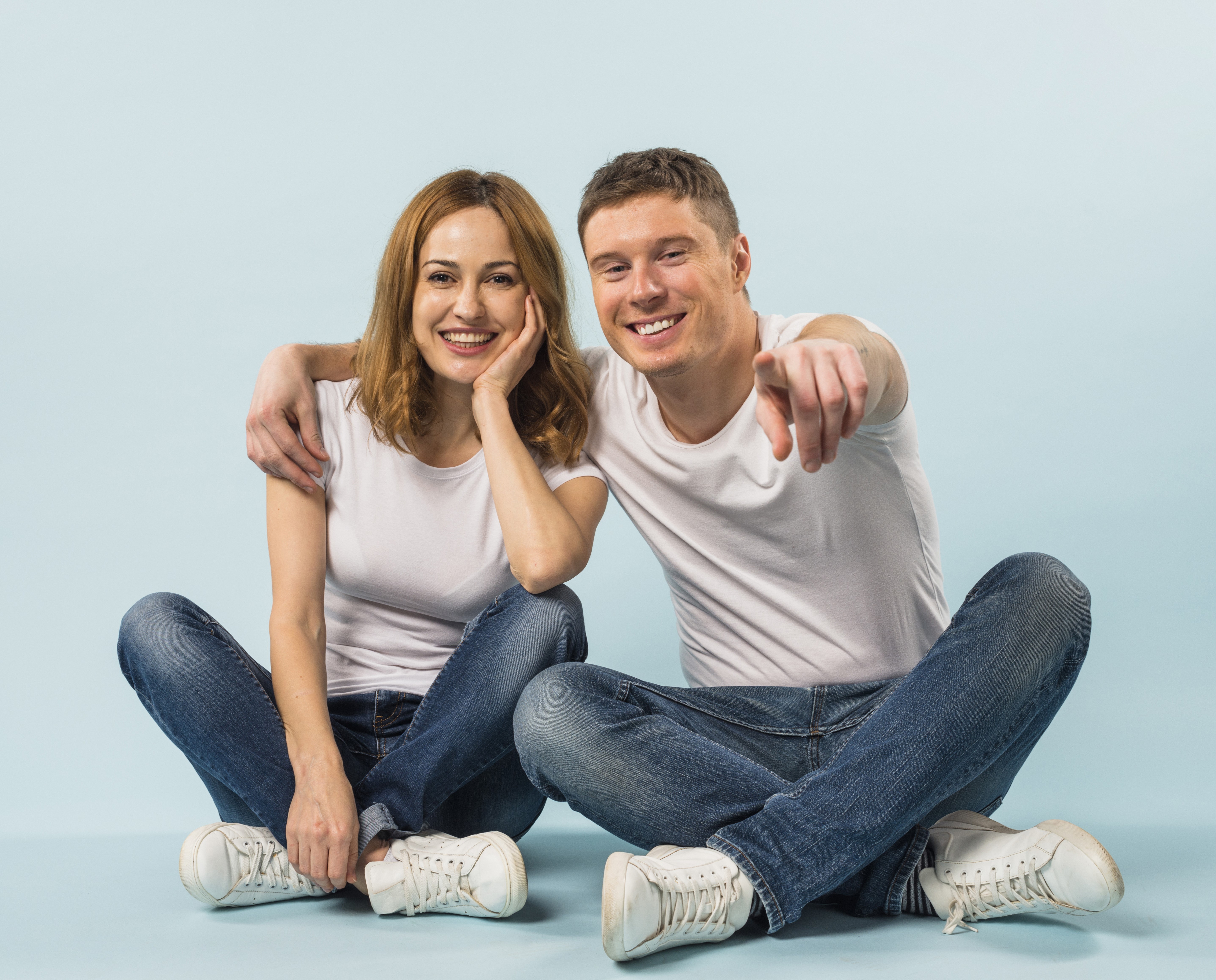 Couple sitting on floor pointing at camera HD Wallpaper