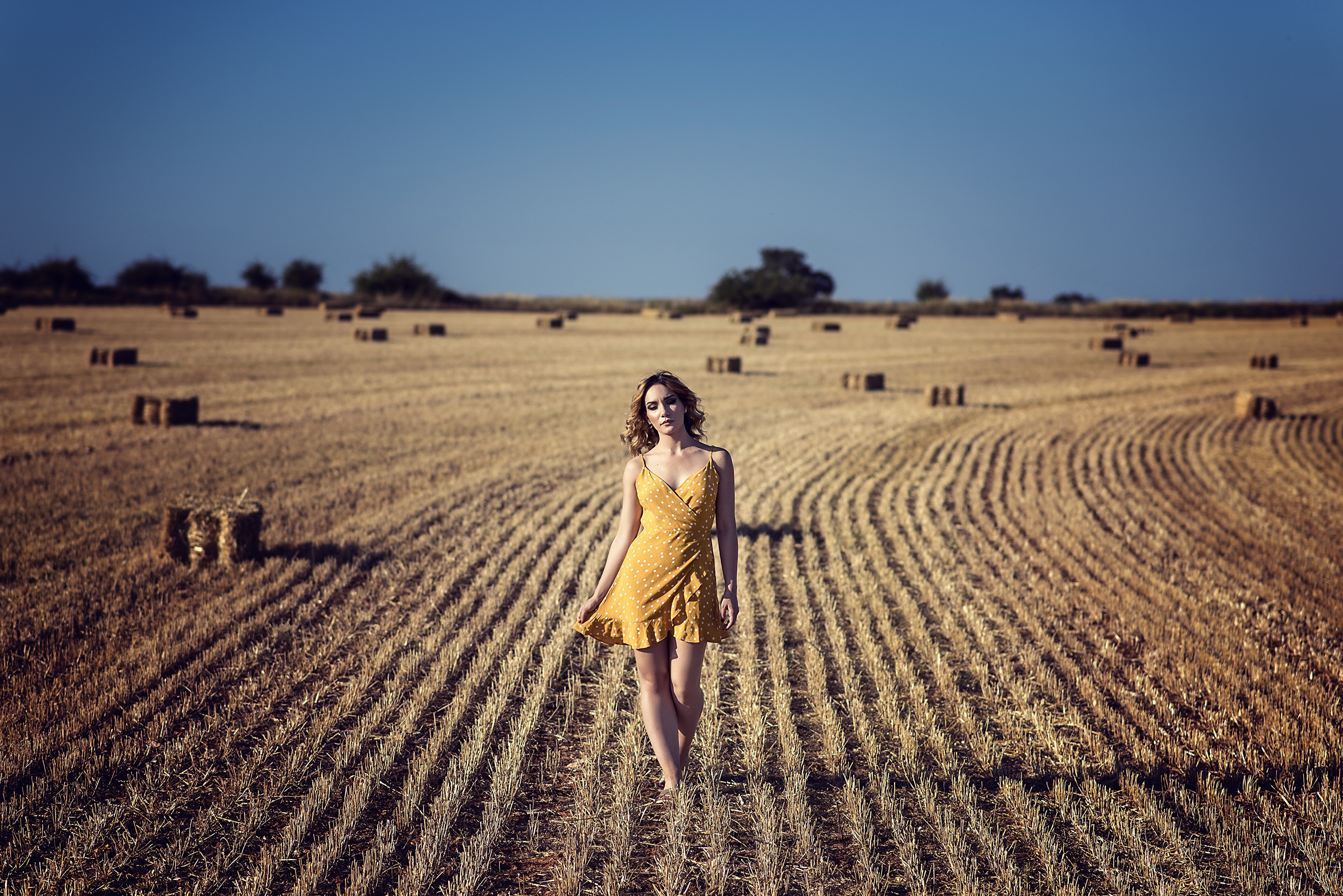 Woman in yellow dress in a field with hay bales HD Wallpaper