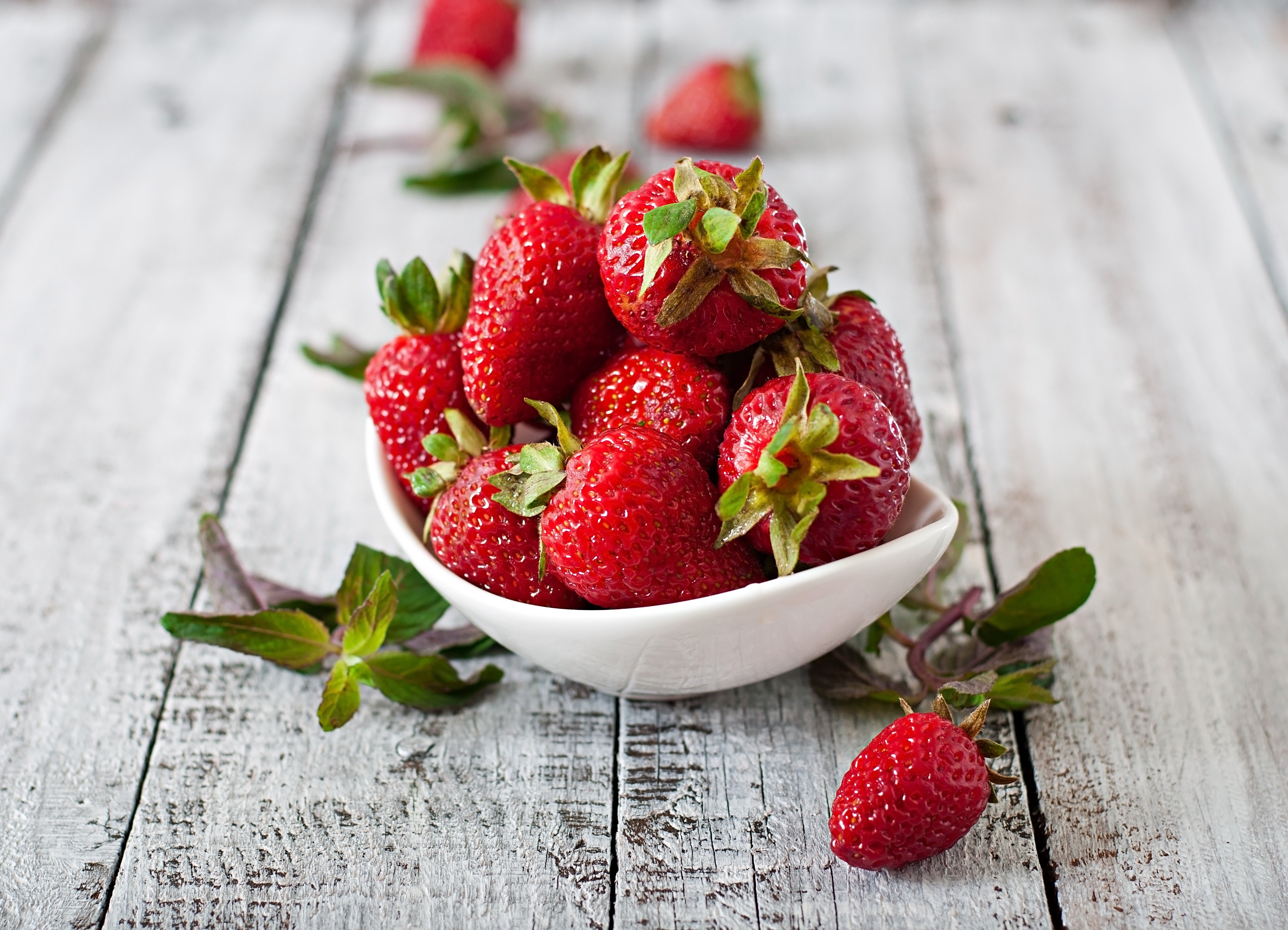 Strawberries in a white bowl on a wooden table HD Wallpaper