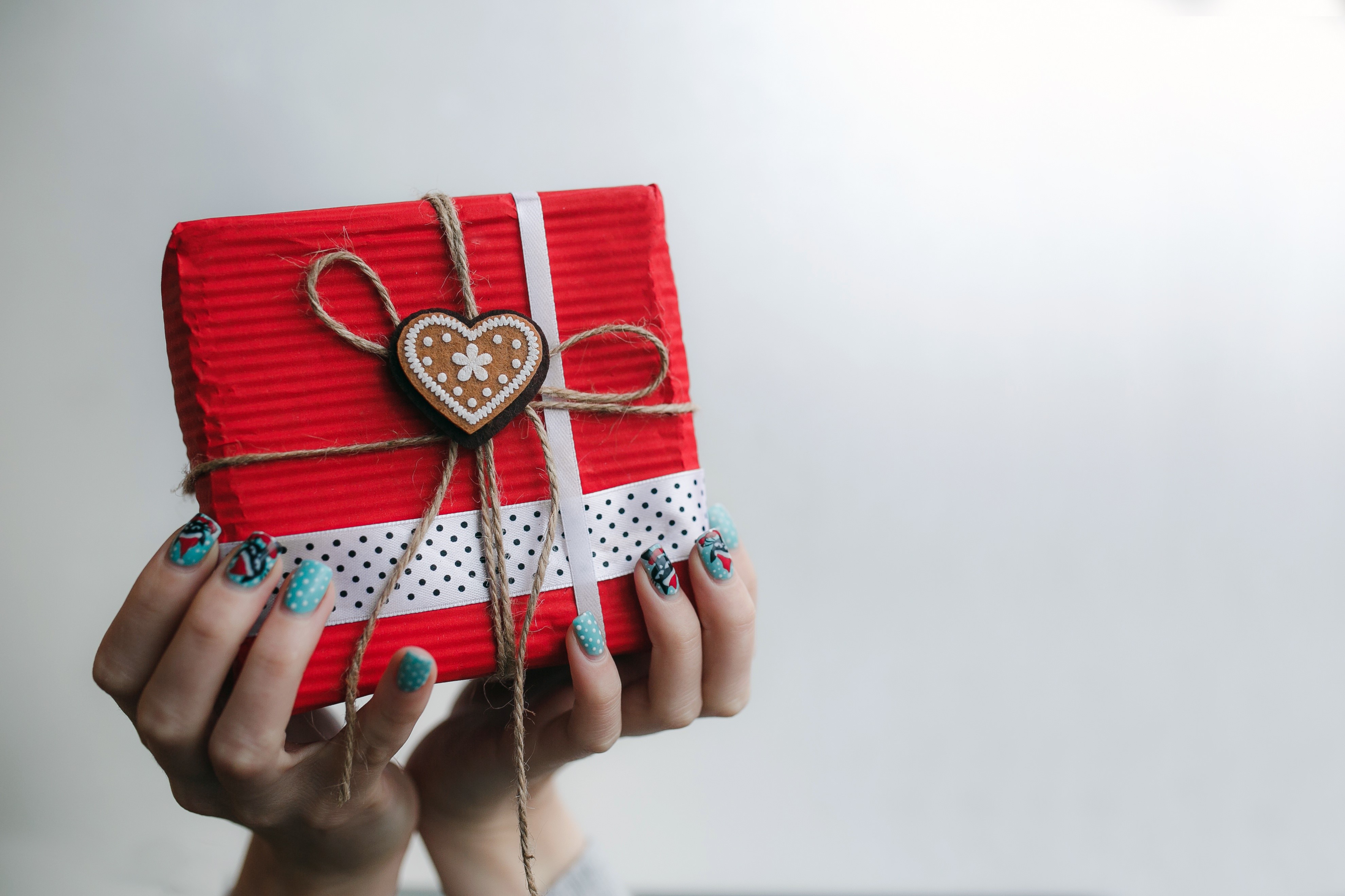 Hands holding a red gift box with heart decoration HD Wallpaper