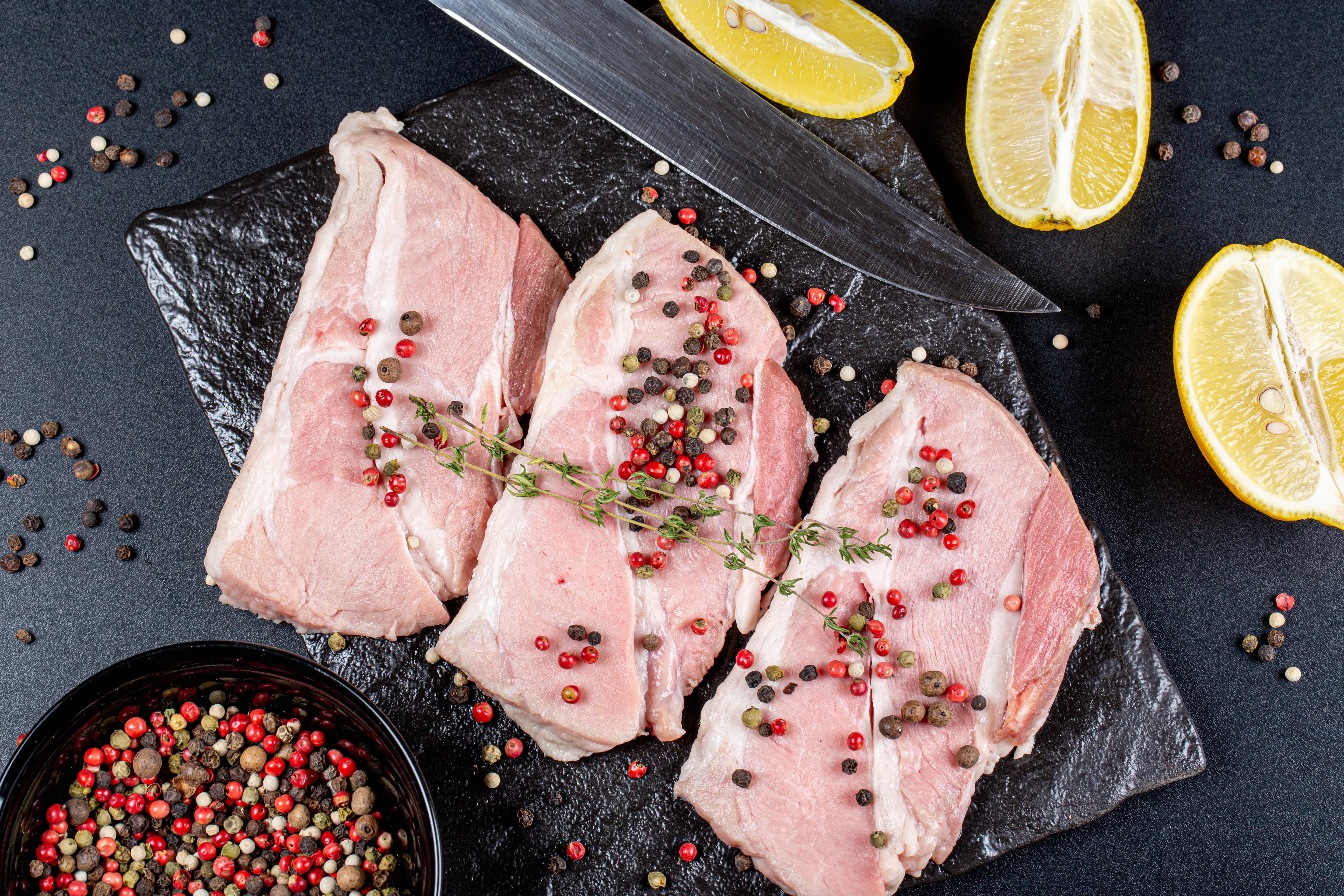Raw meat with peppercorns and lemons on a cutting board HD Wallpaper