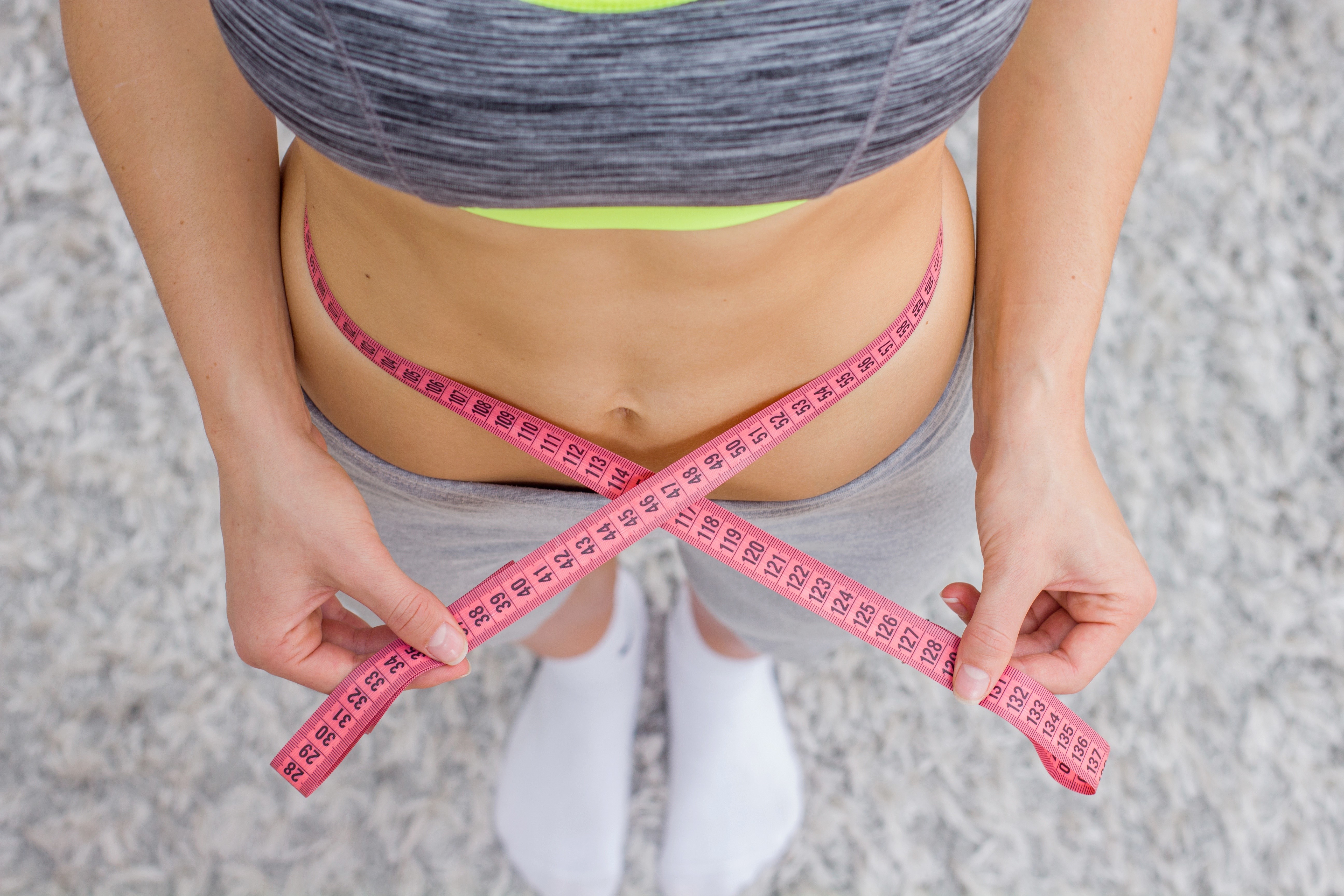 Woman measuring her waist with a tape measure HD Wallpaper