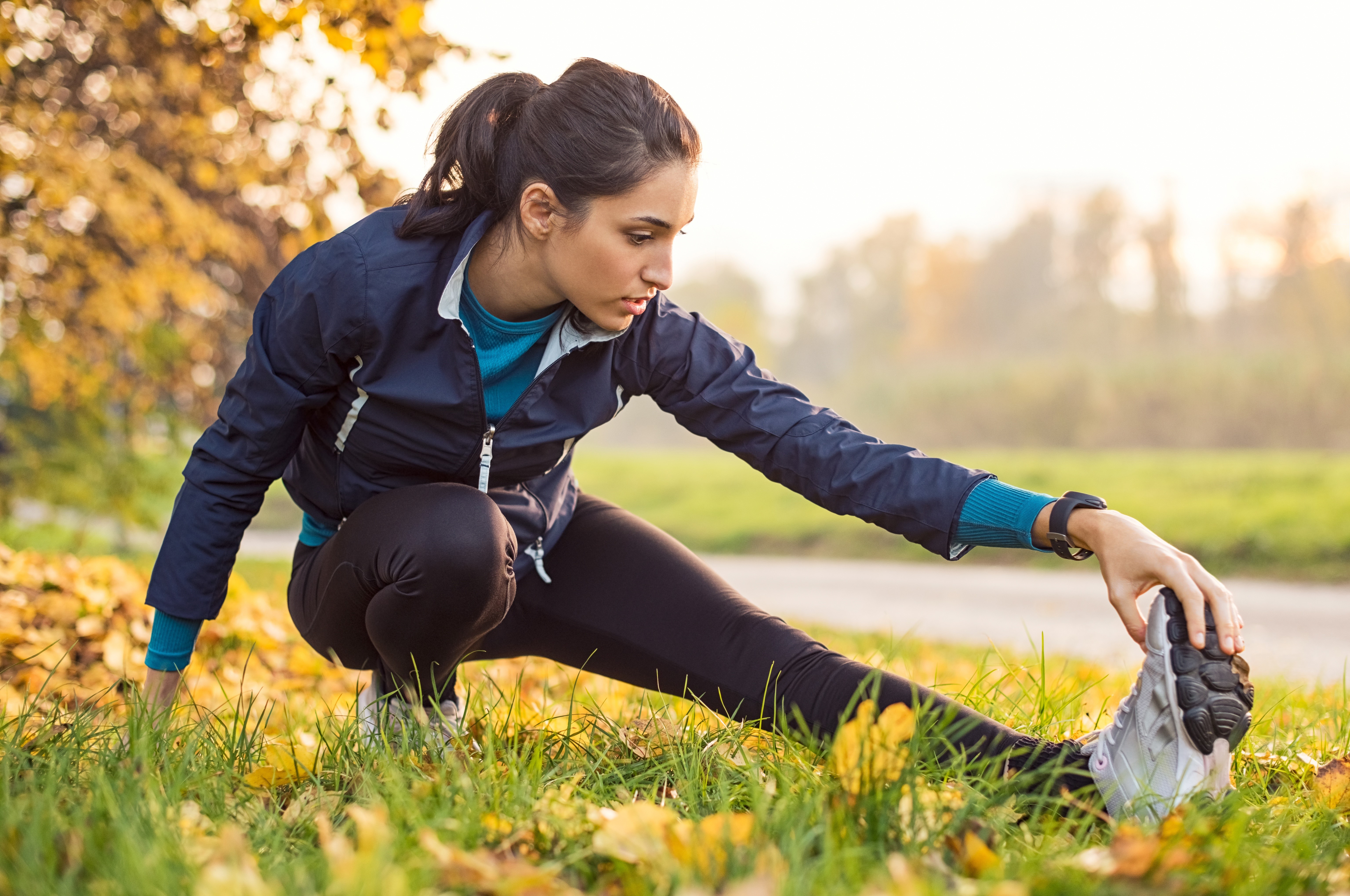 Woman stretching in a park during autumn HD Wallpaper