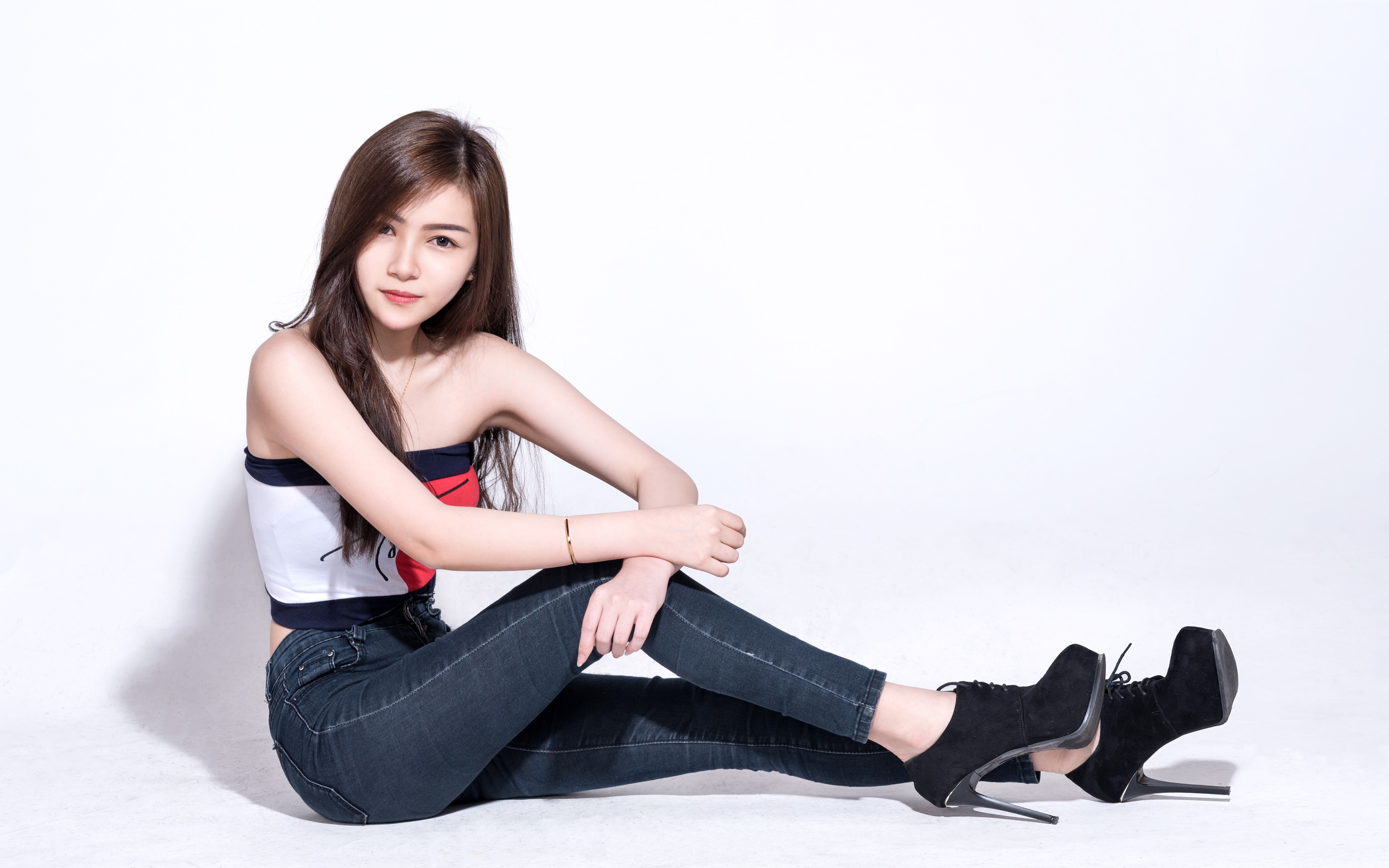 Asian woman with brown hair sitting in jeans and stilettos HD Wallpaper