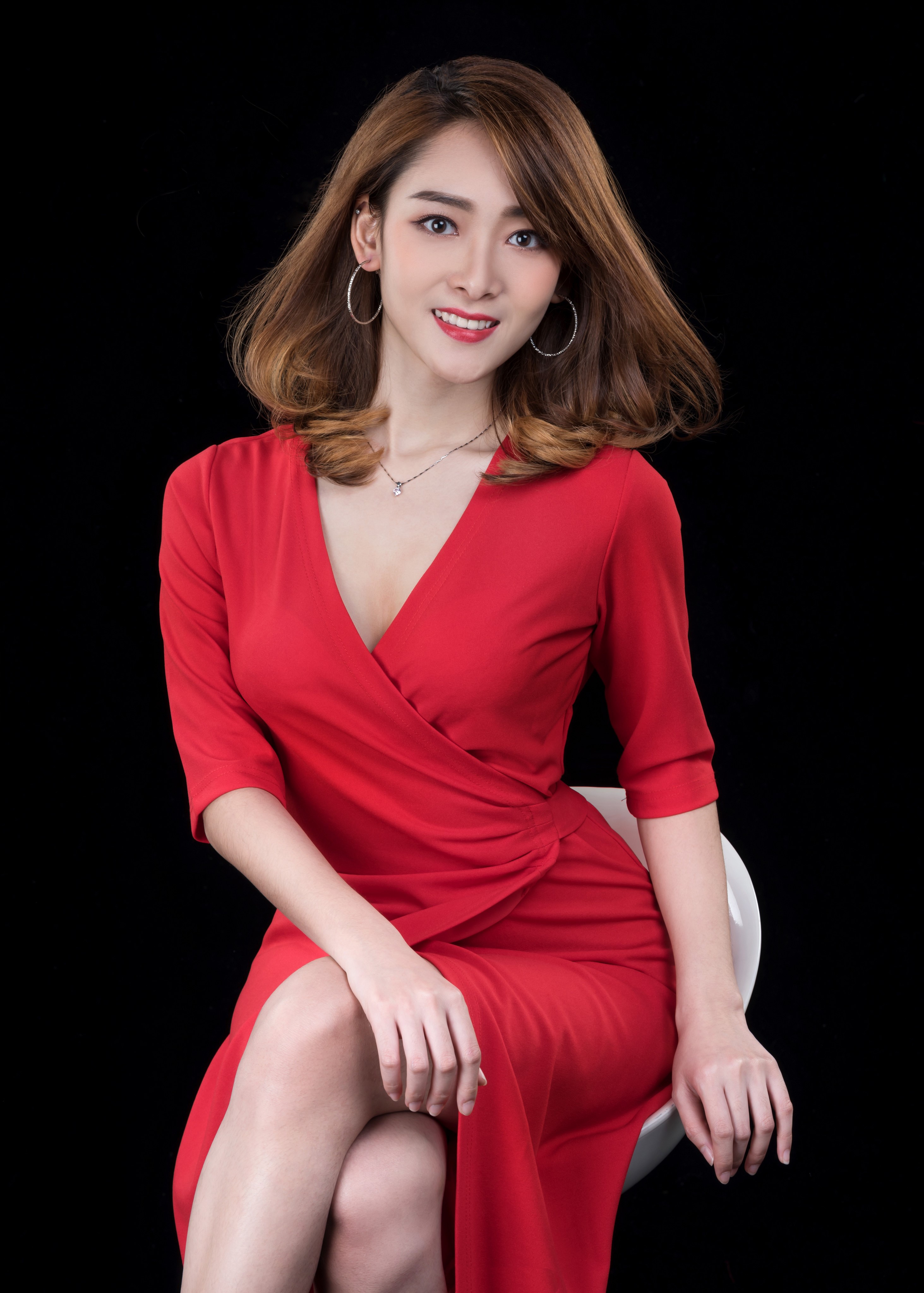 Asian woman in red dress sitting against black background HD Phone Wallpaper