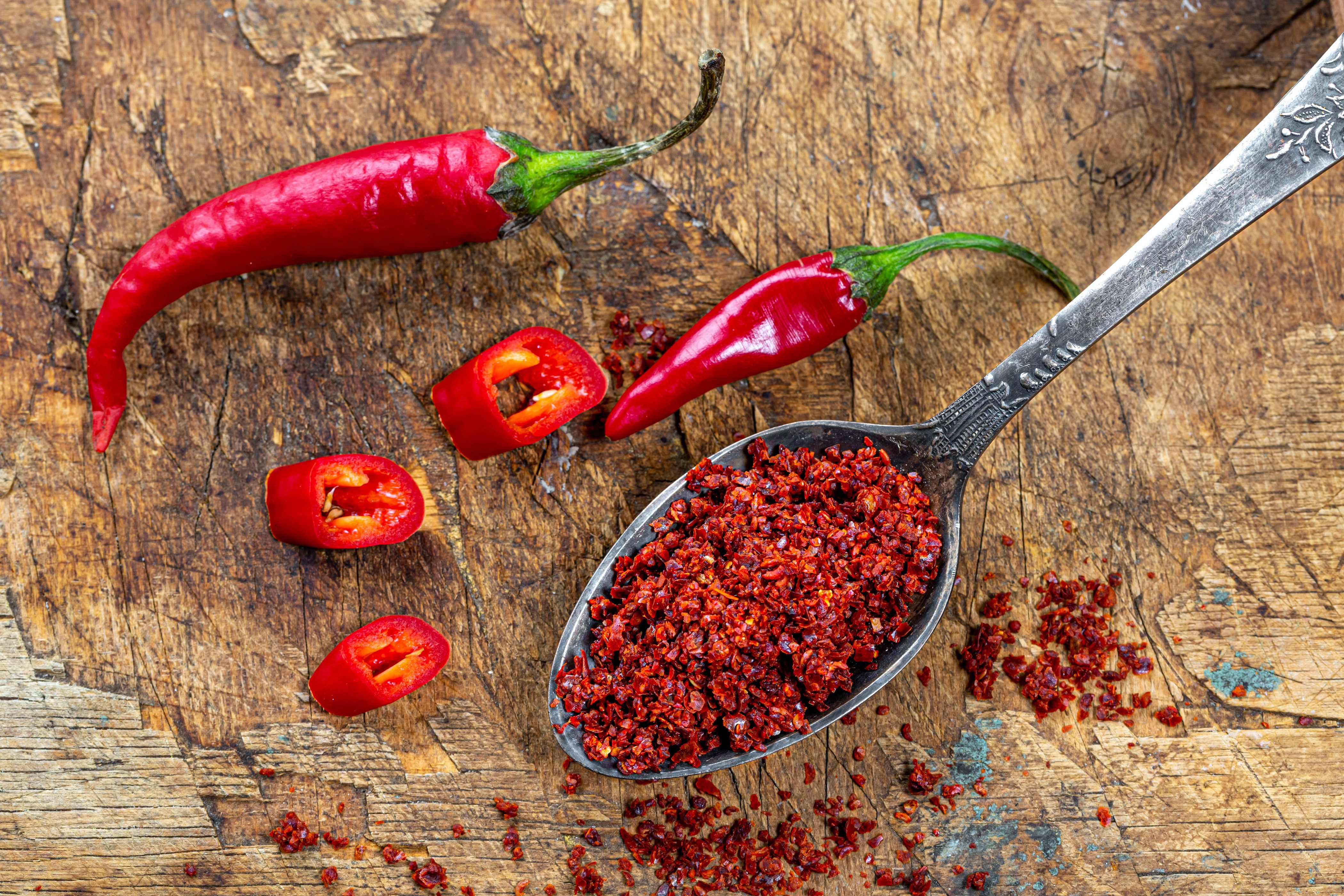 Red chili peppers and flakes on wood HD Wallpaper