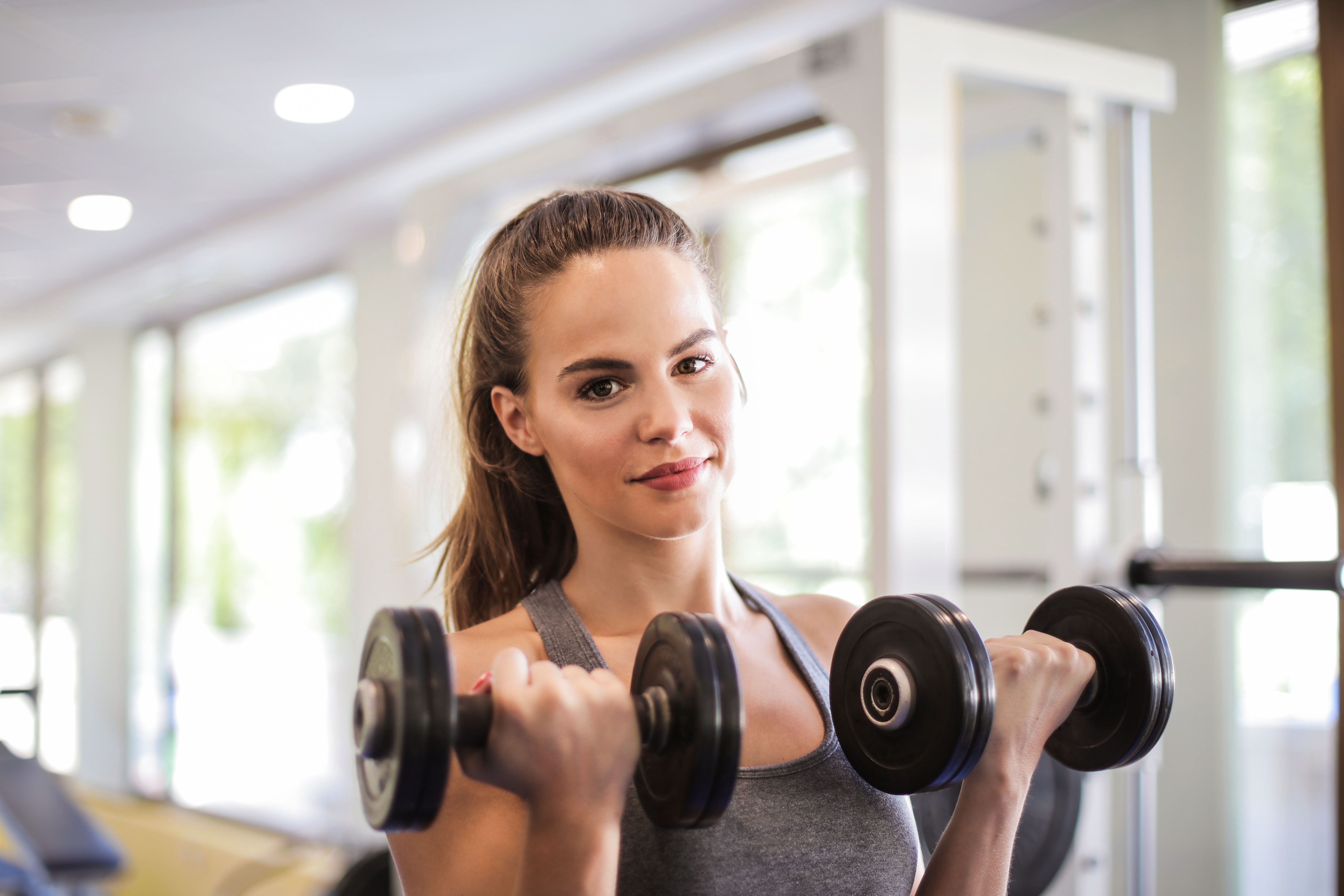 Woman lifting dumbbells in a gym HD Wallpaper