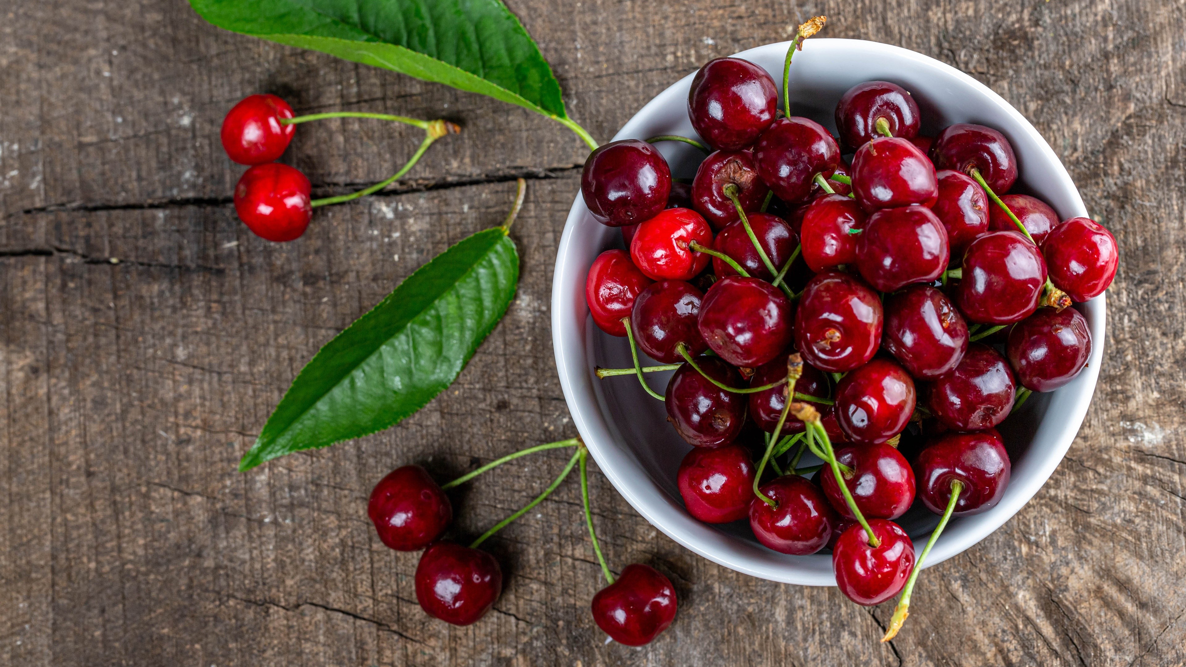 Cherries in a bowl on a wooden table HD Wallpaper