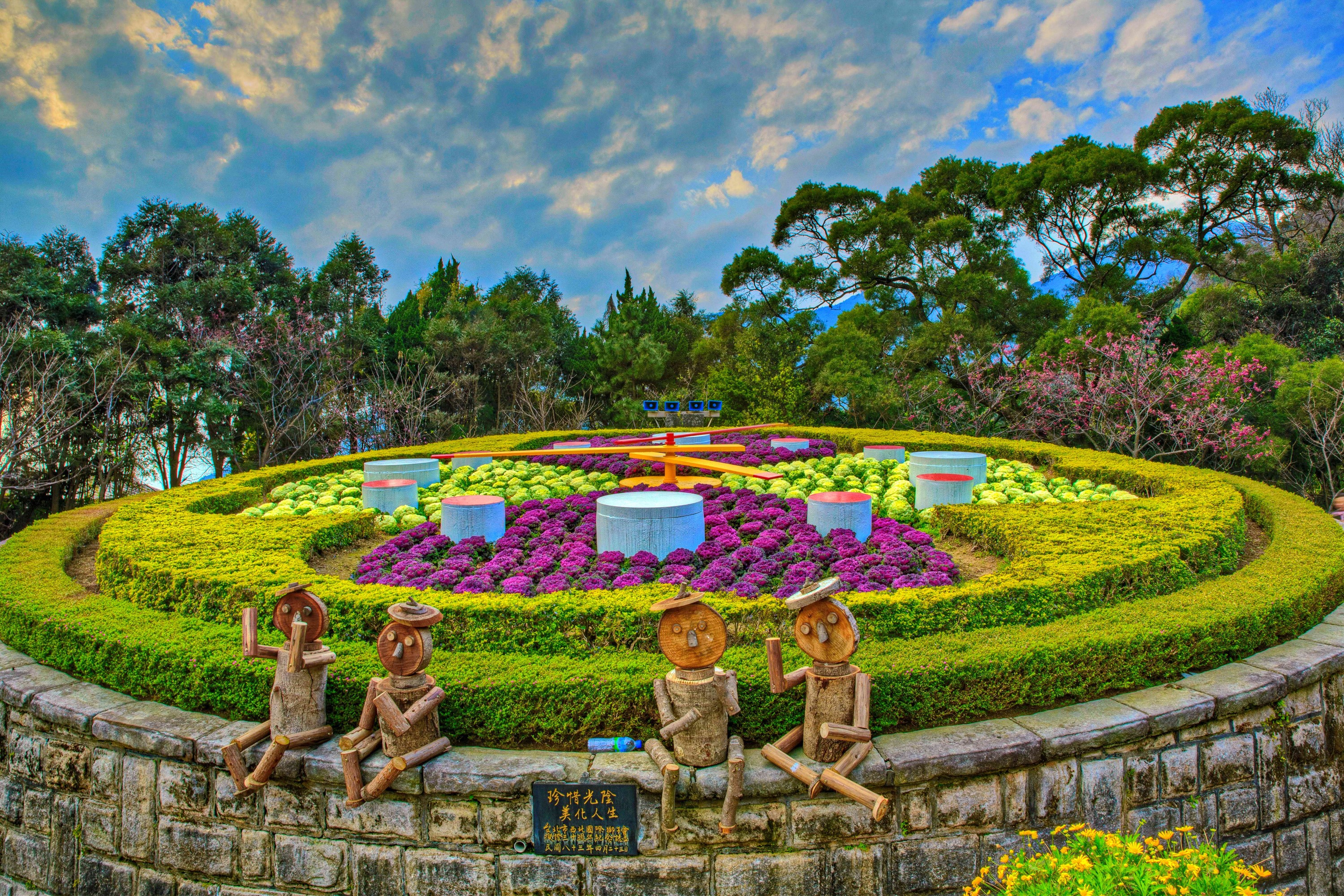 Flower clock sculpture garden with wooden figures in Taiwan HD Wallpaper