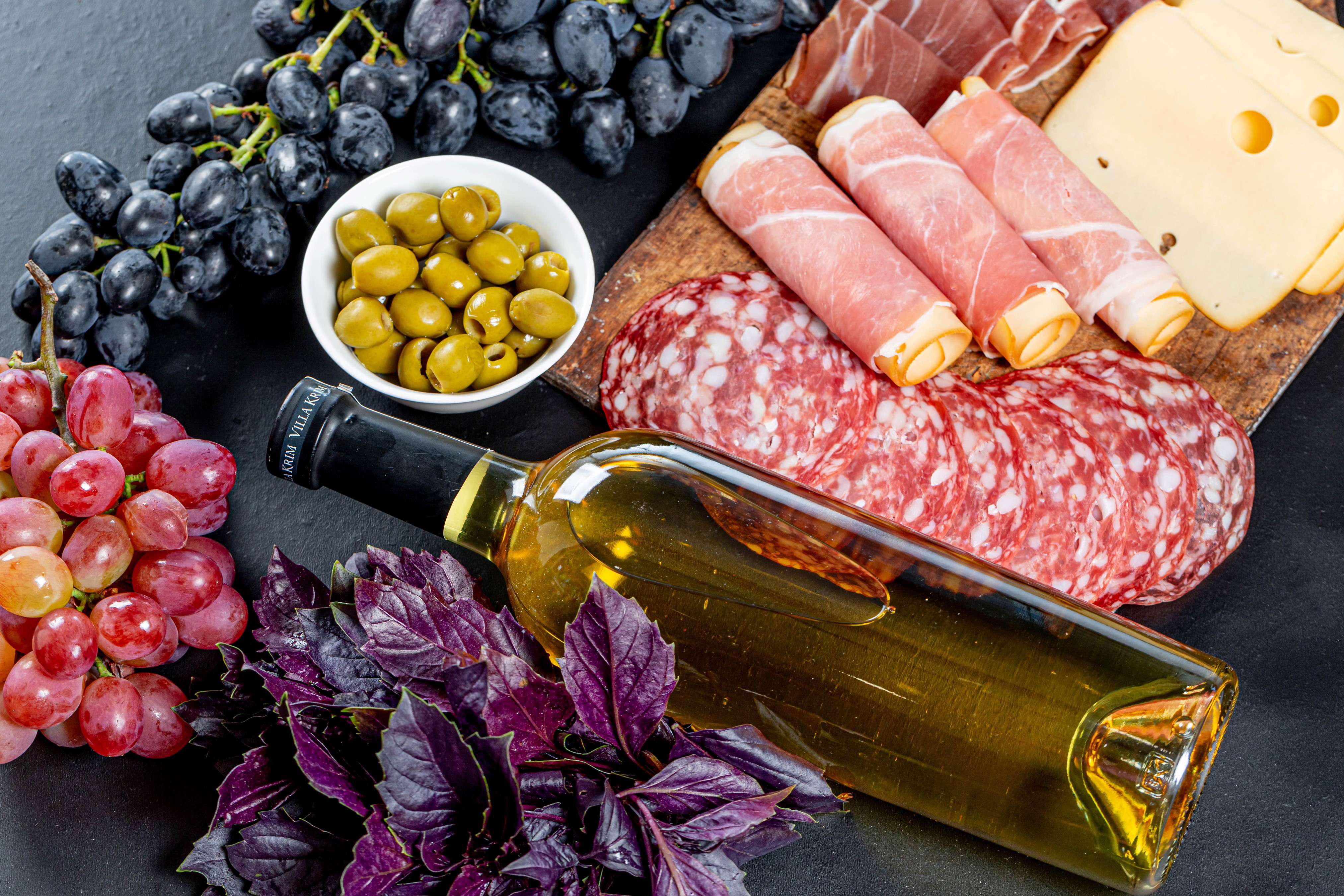 Charcuterie board with grapes, olives, wine, and basil HD Wallpaper