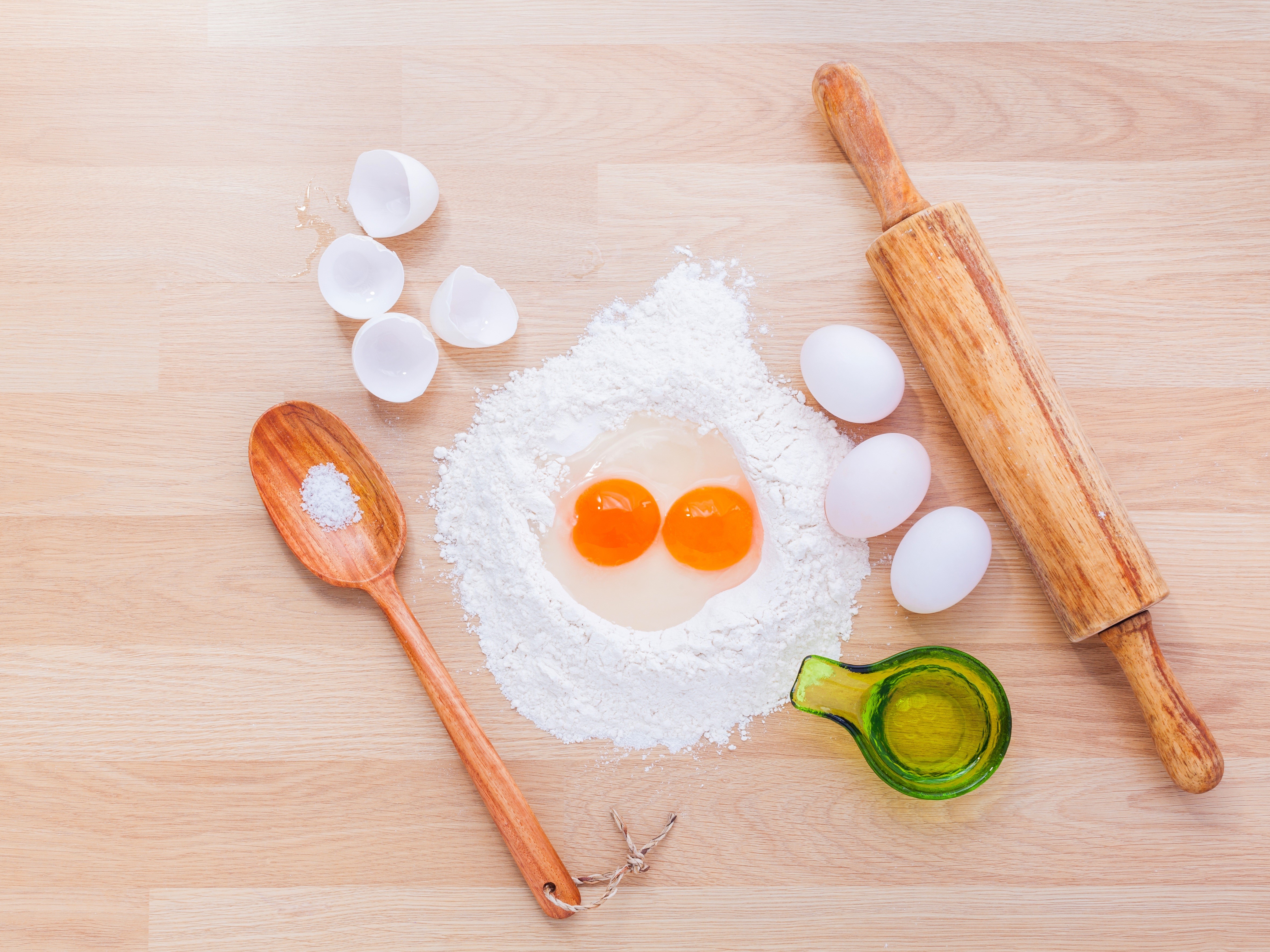 Flour, eggs, salt, oil, and rolling pin on a wooden table HD Wallpaper