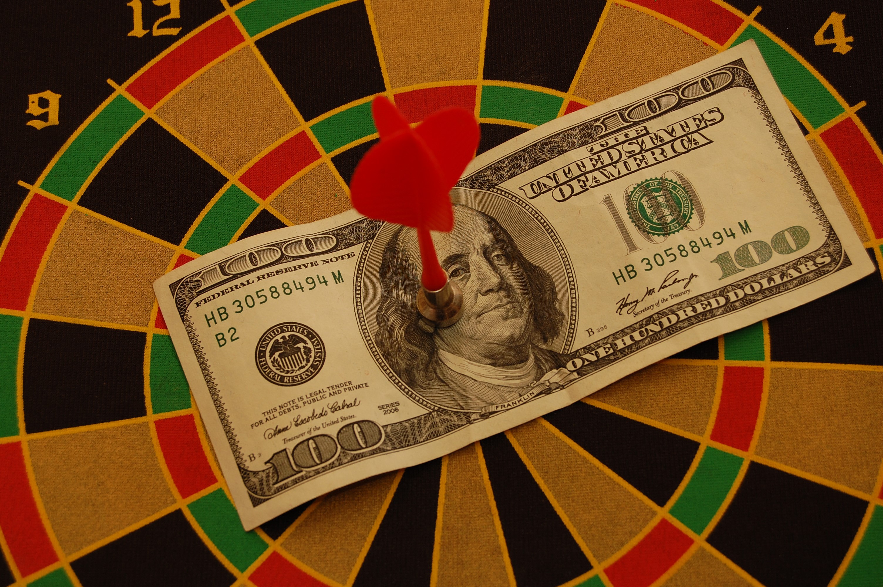One Hundred Dollar Bill on Dartboard with Dart HD Wallpaper