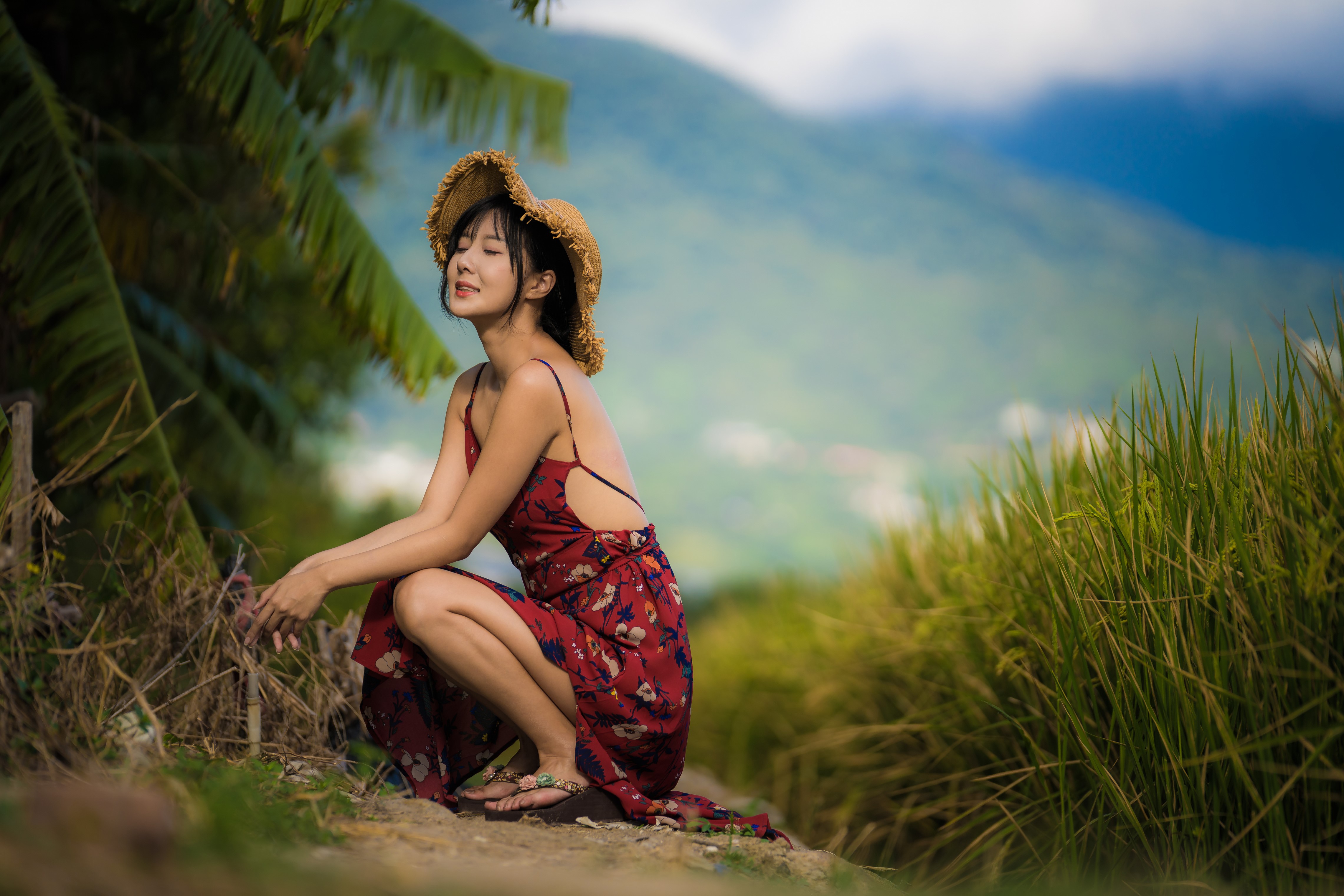Asian woman in dress and hat sitting in nature HD Wallpaper