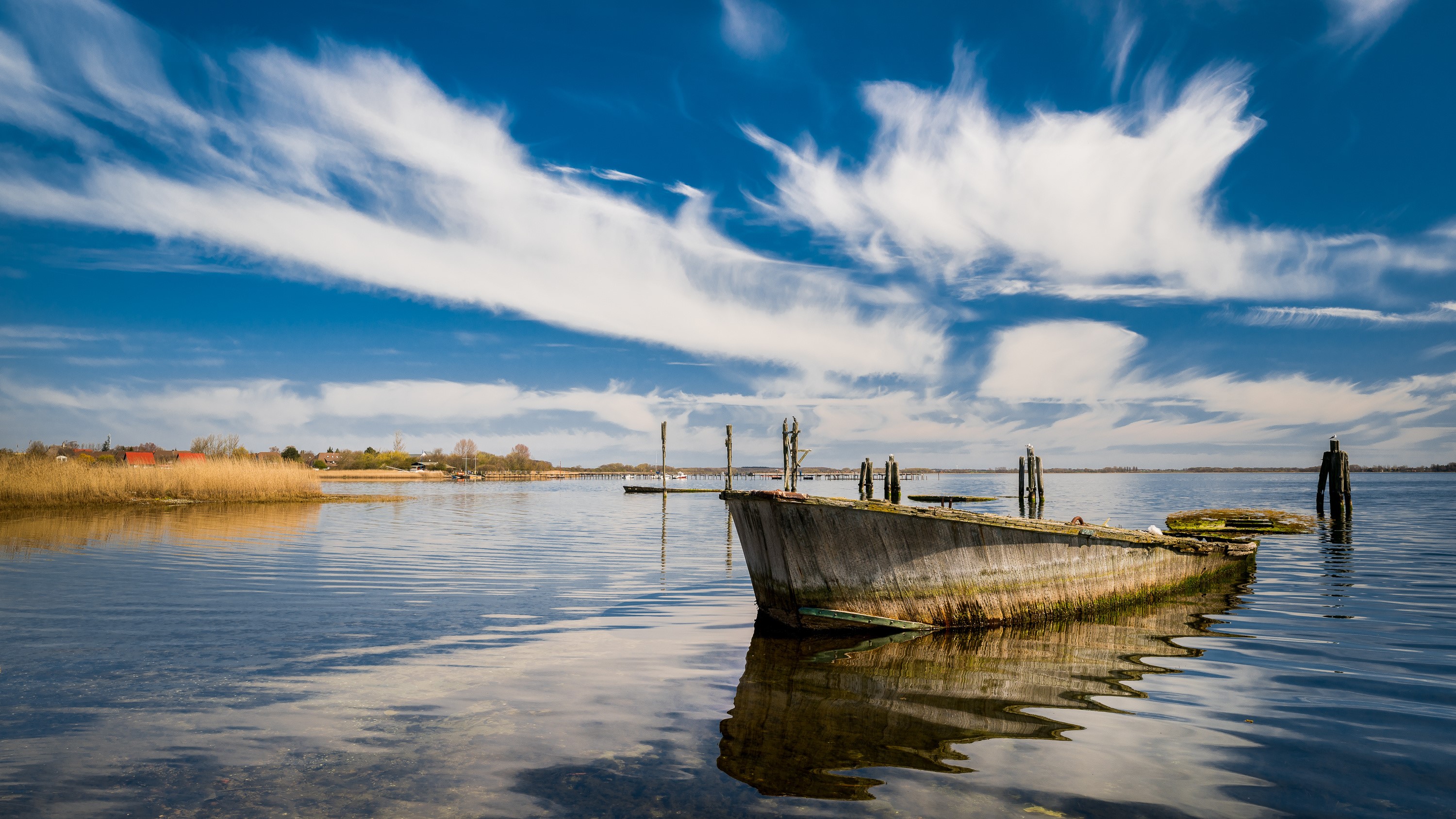Abandoned boat on a lake under a cloudy sky HD Wallpaper