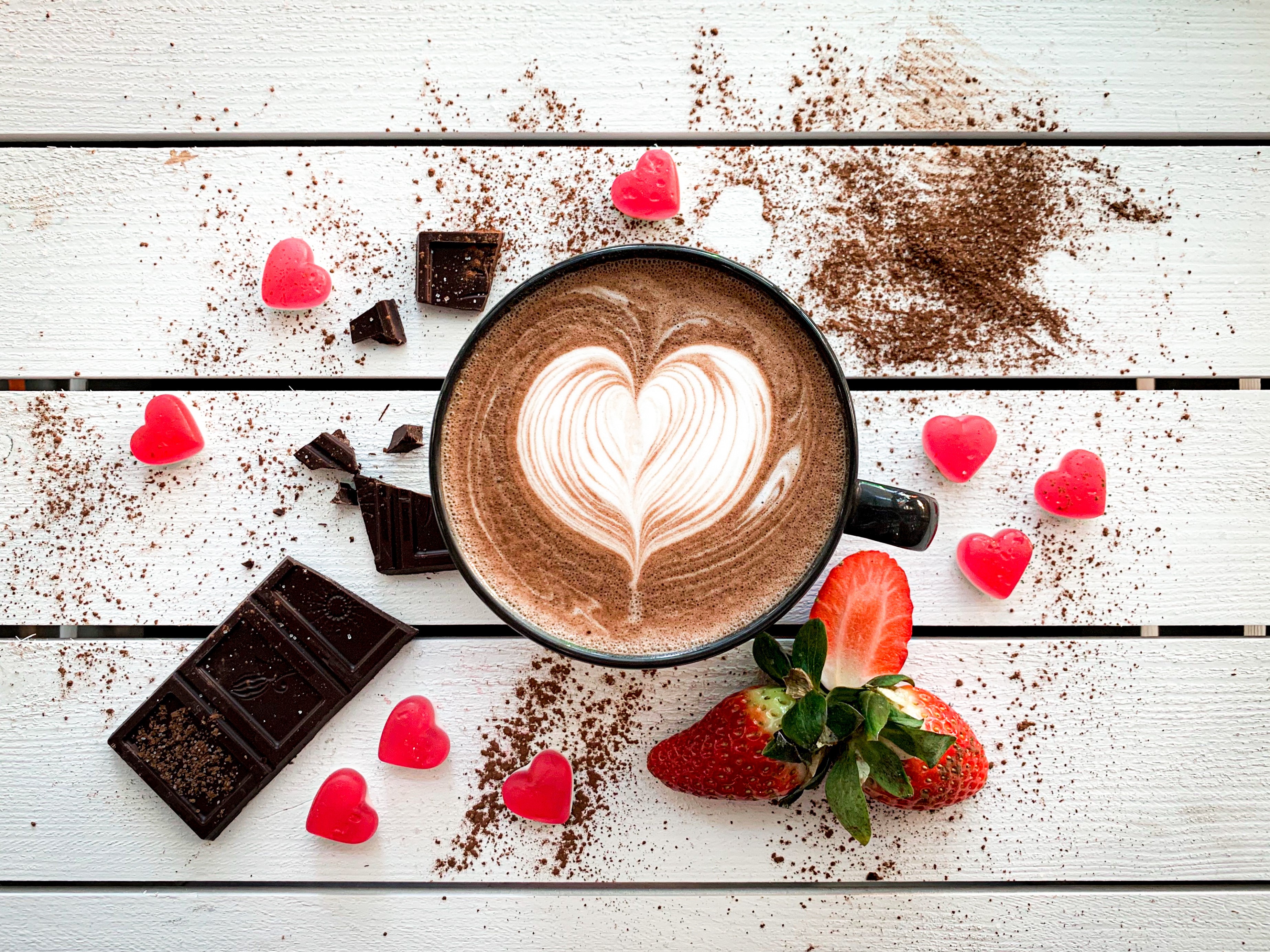 Hot chocolate with latte art, chocolate, strawberries, and heart candies HD Wallpaper