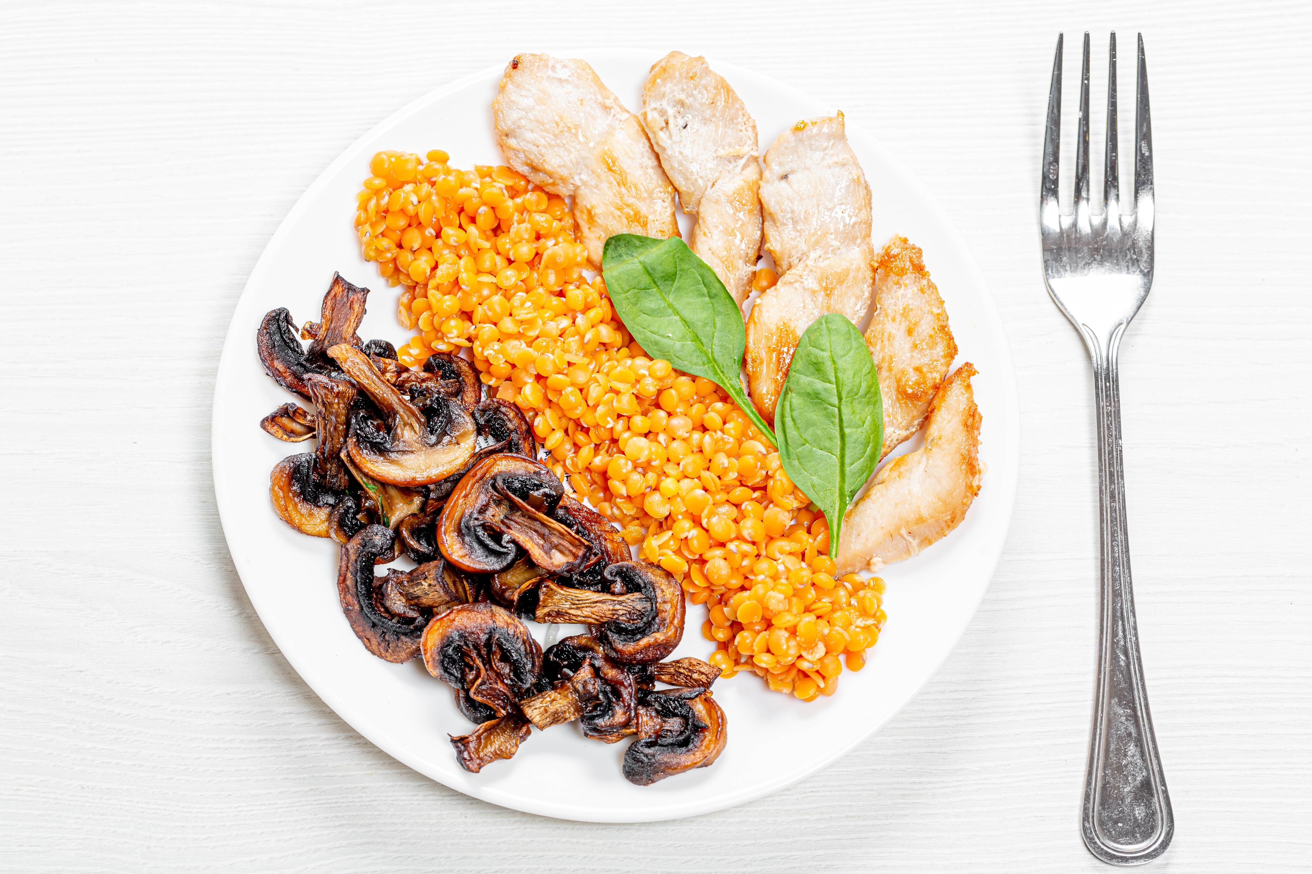 Chicken breast with lentils, mushrooms, and spinach on a plate with a fork HD Wallpaper