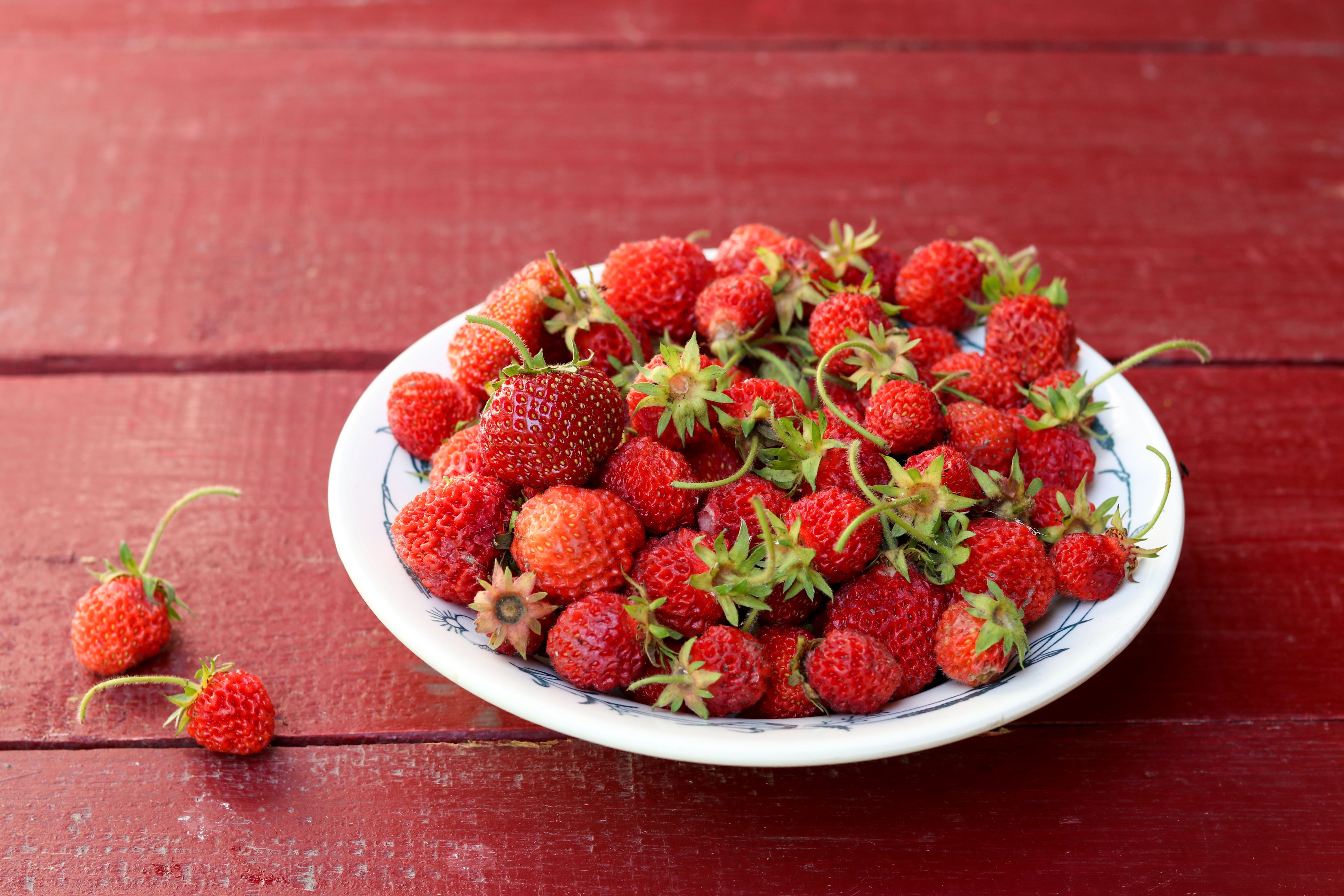 Strawberries in a plate on a red wooden table HD Wallpaper