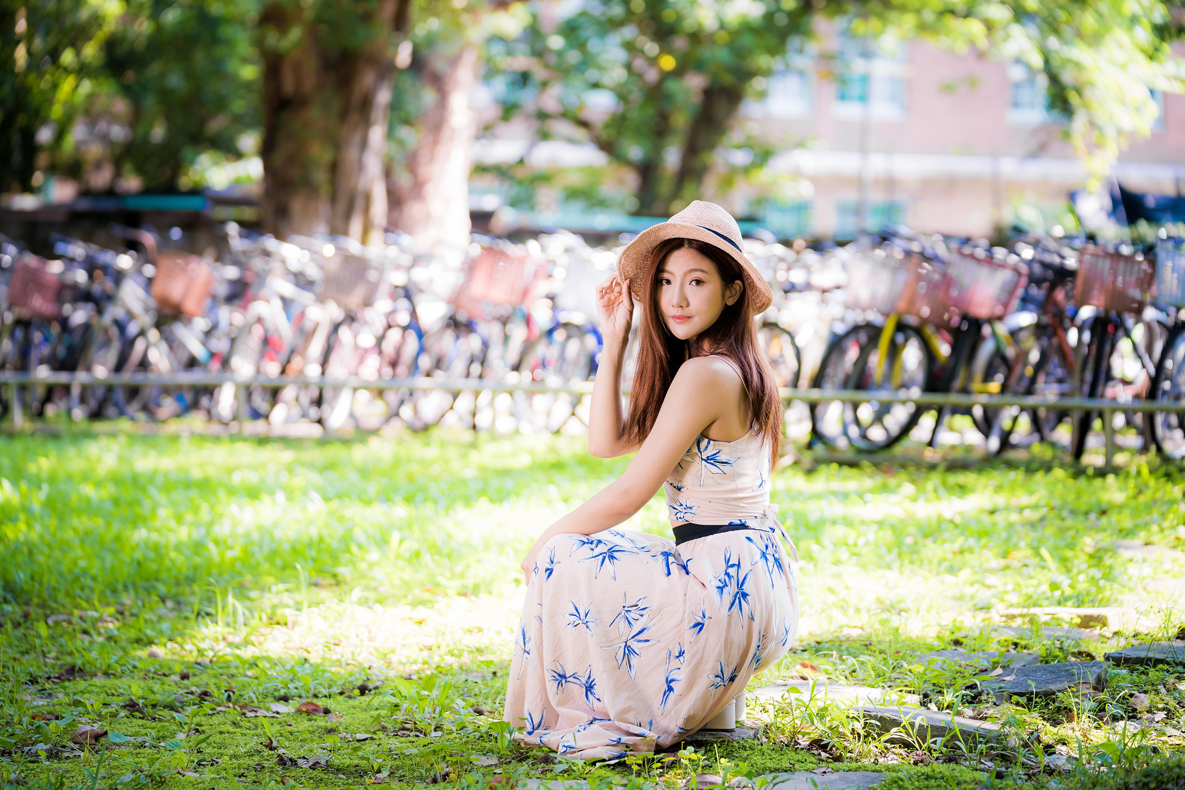 Asian woman in a dress and hat sitting in a park HD Wallpaper