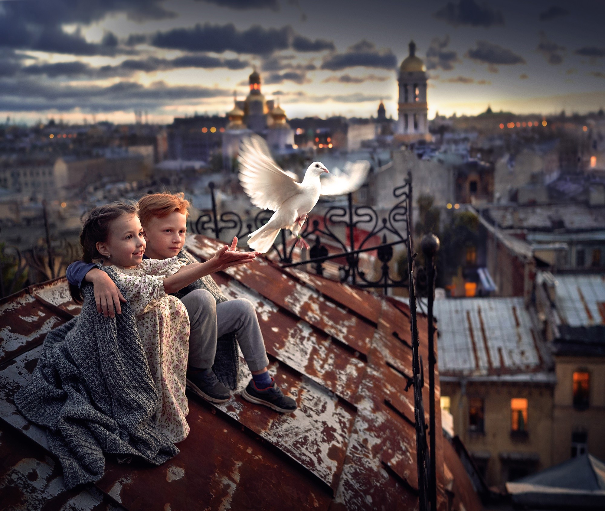 Children on a rooftop releasing a dove over a city at dusk HD Wallpaper