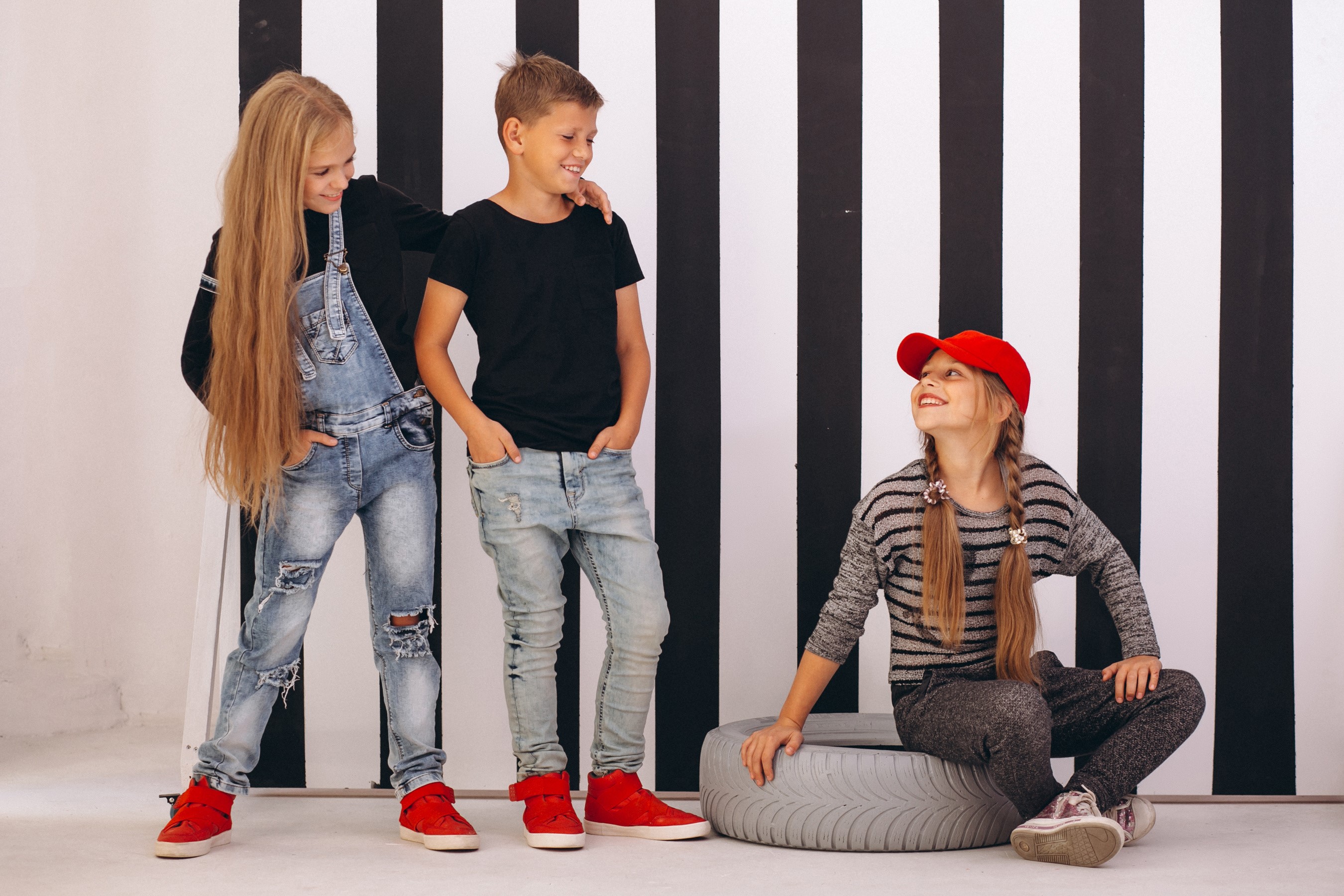 Three children posing in front of a striped background HD Wallpaper