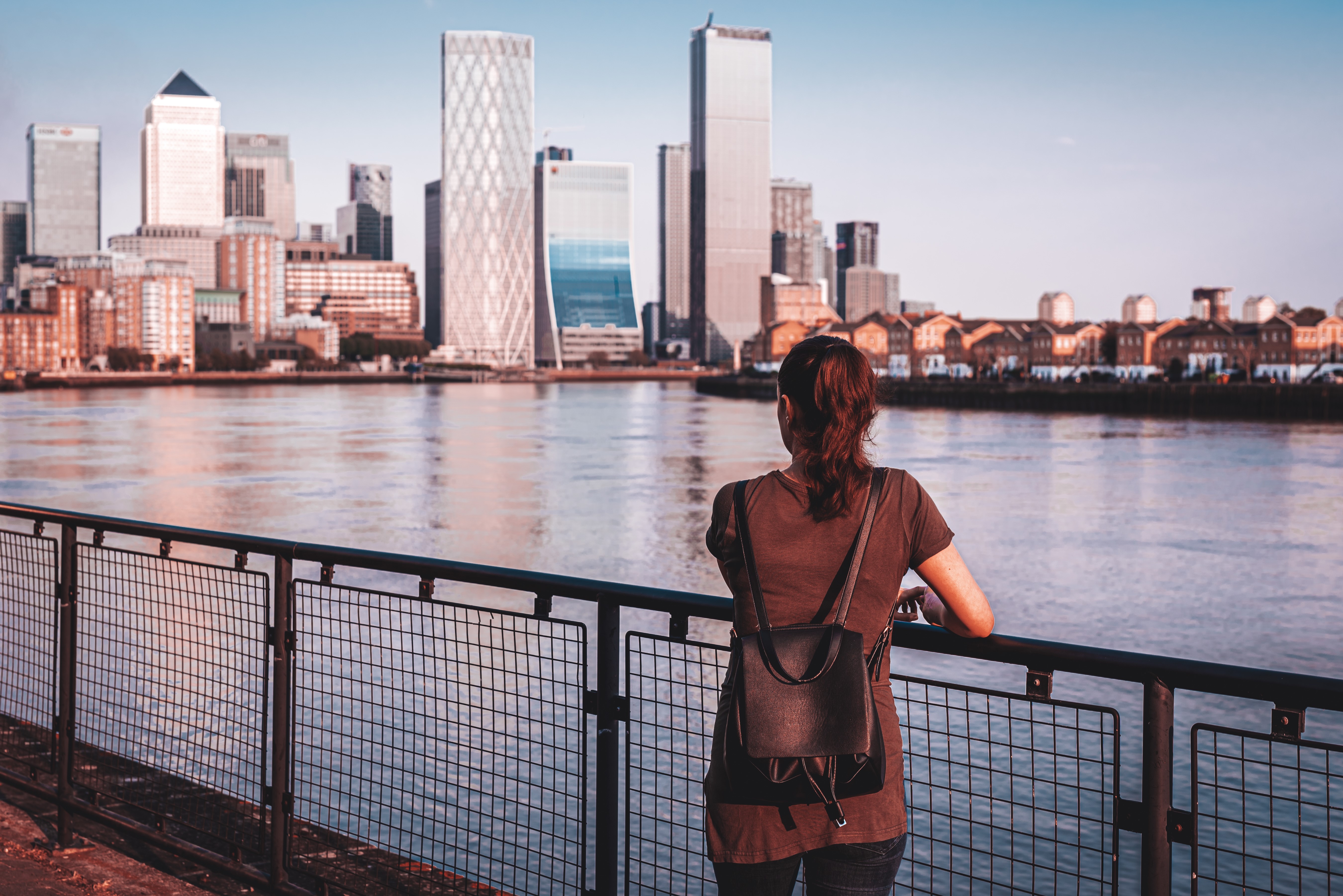 Woman with backpack looking at London skyscrapers across river HD Wallpaper