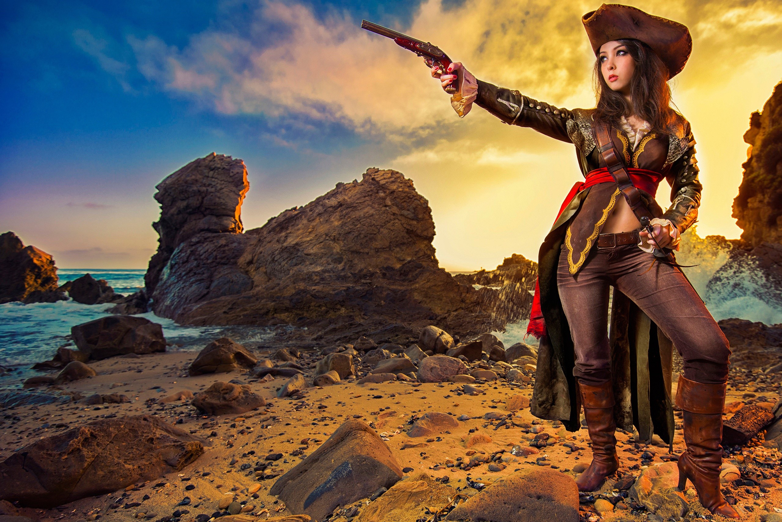 Woman in pirate costume with pistol on rocky beach HD Wallpaper