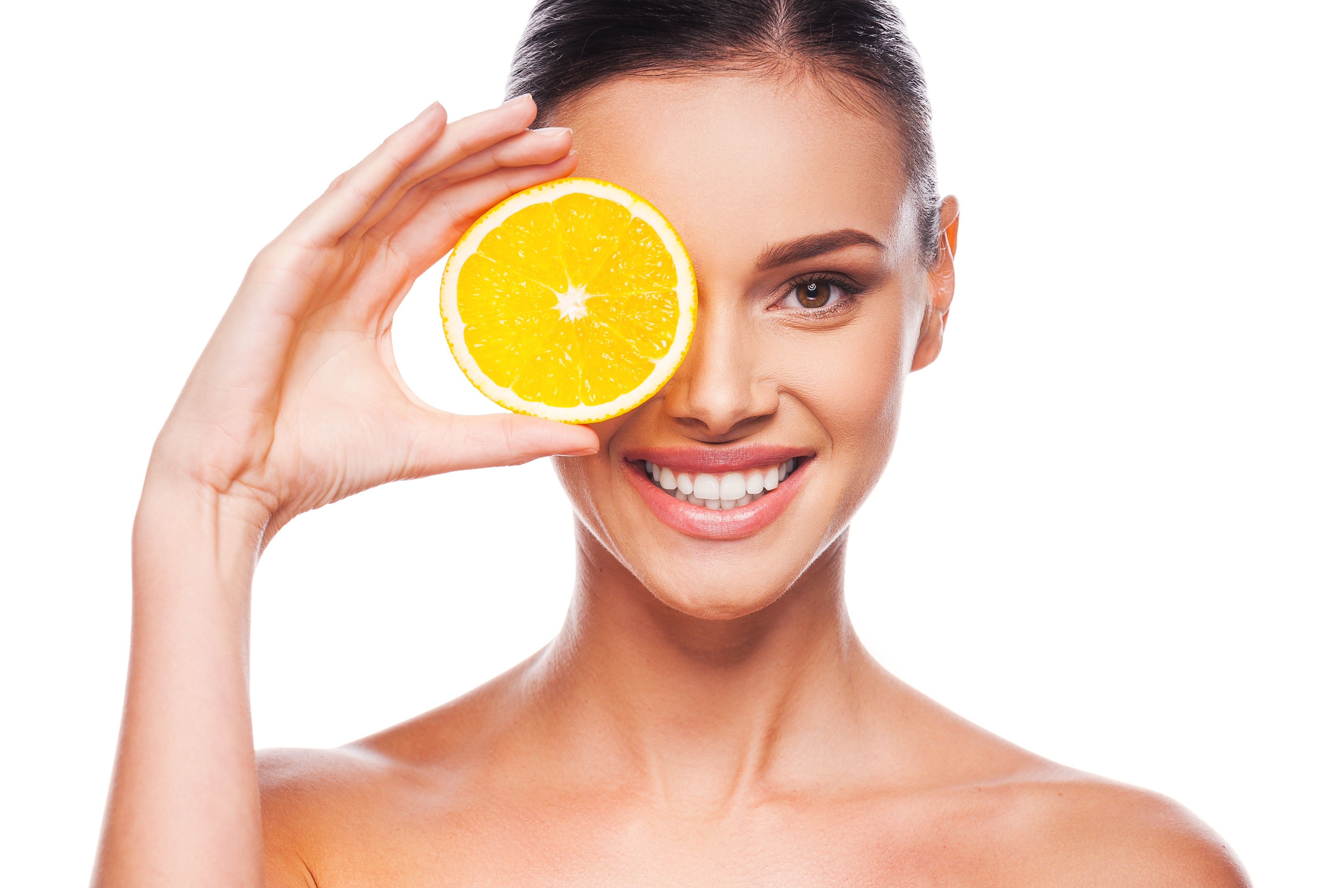 Model holding orange slice over eye HD Wallpaper