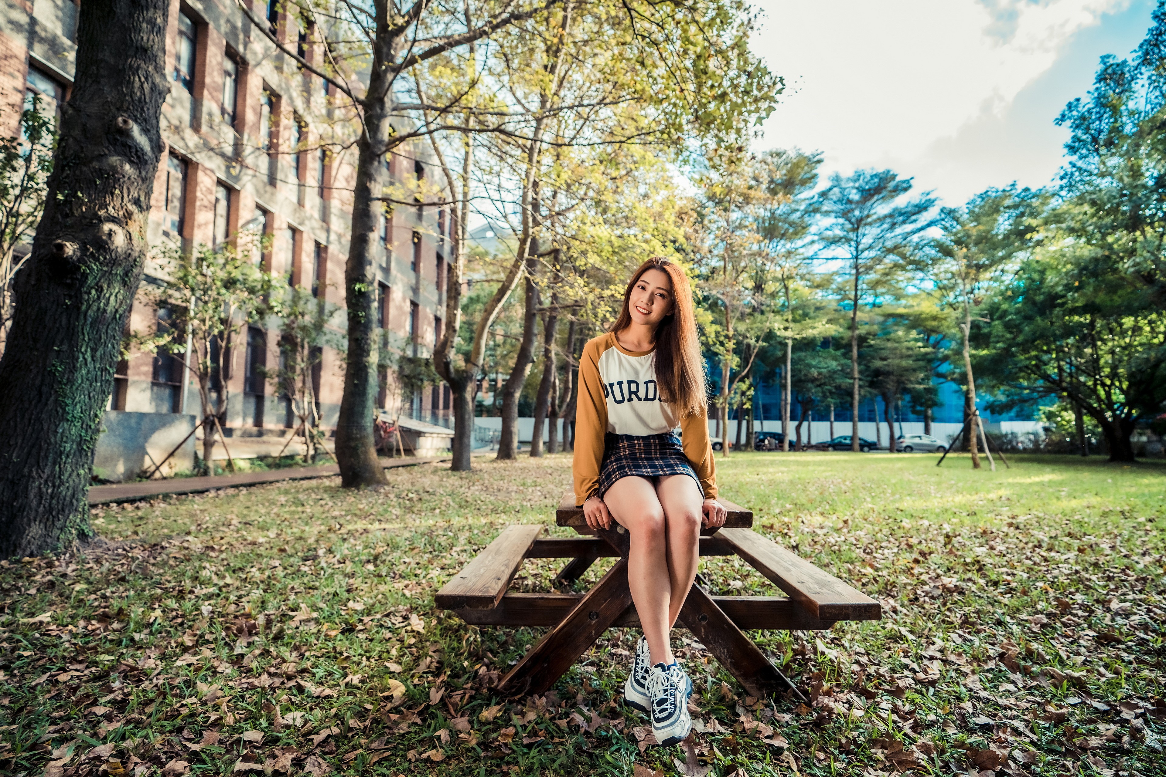 Asian woman sitting on a picnic table in a park HD Wallpaper