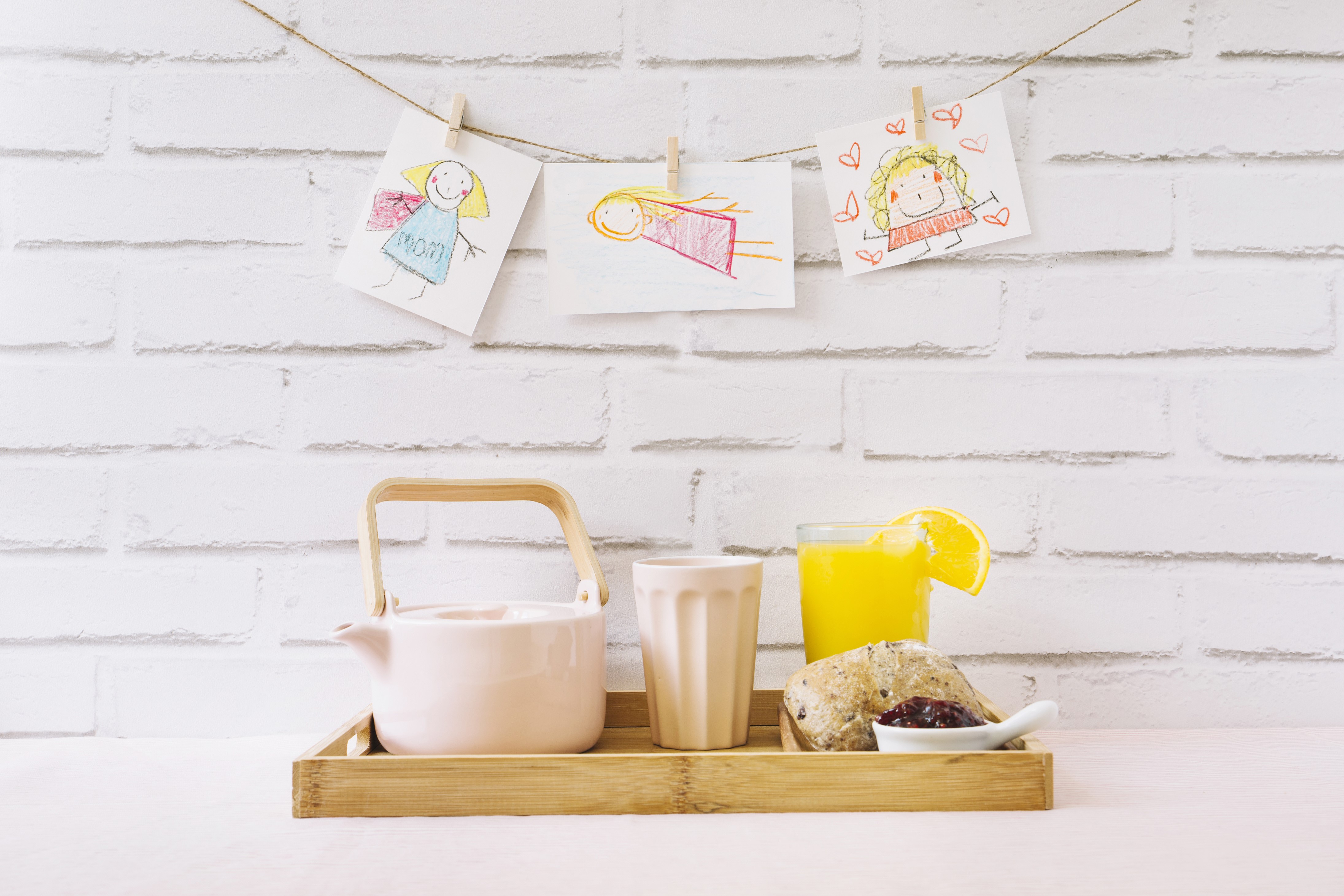 Breakfast tray with kettle, juice, pastry, and children's drawings HD Wallpaper