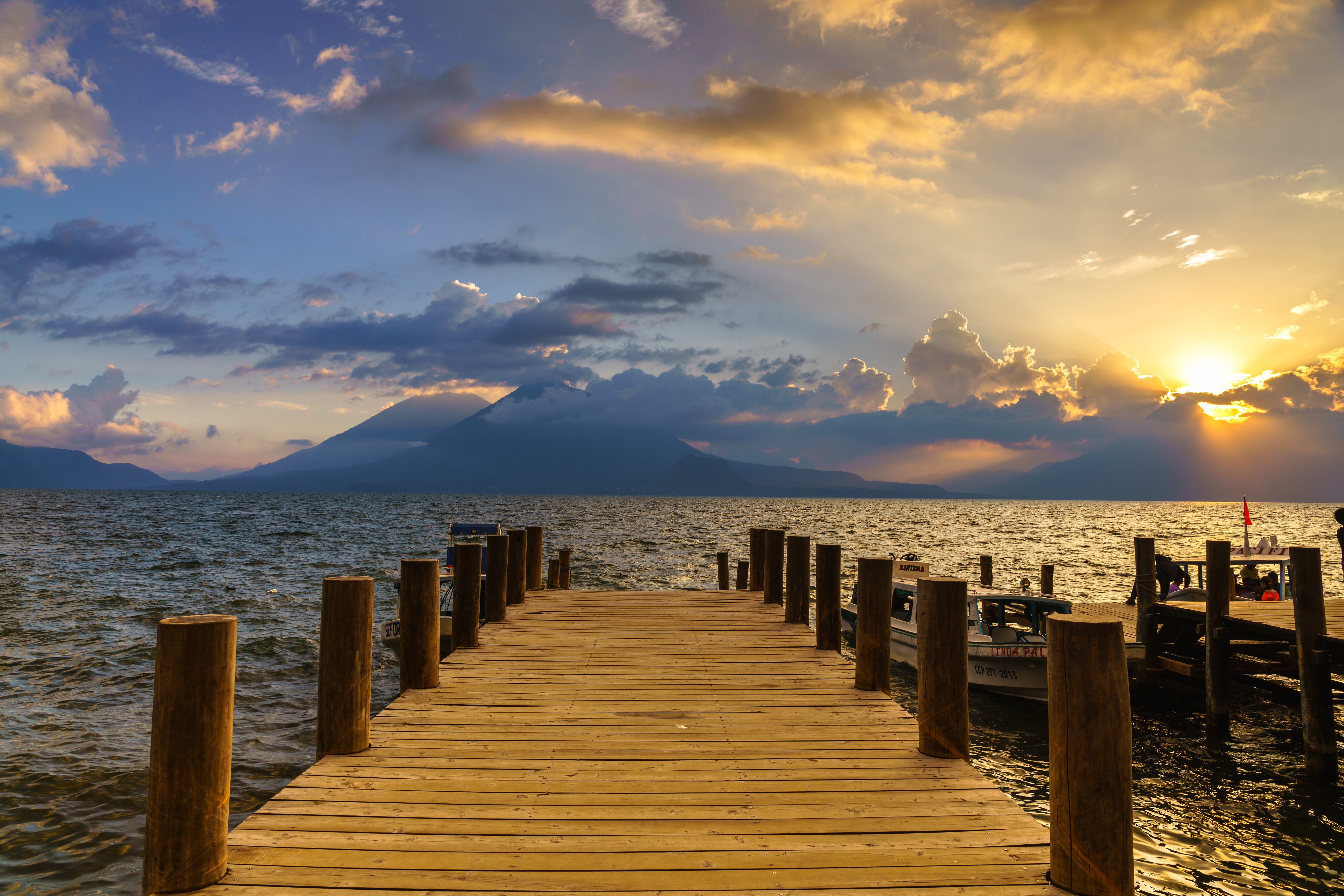 Wooden dock on a lake with mountains at sunset HD Wallpaper