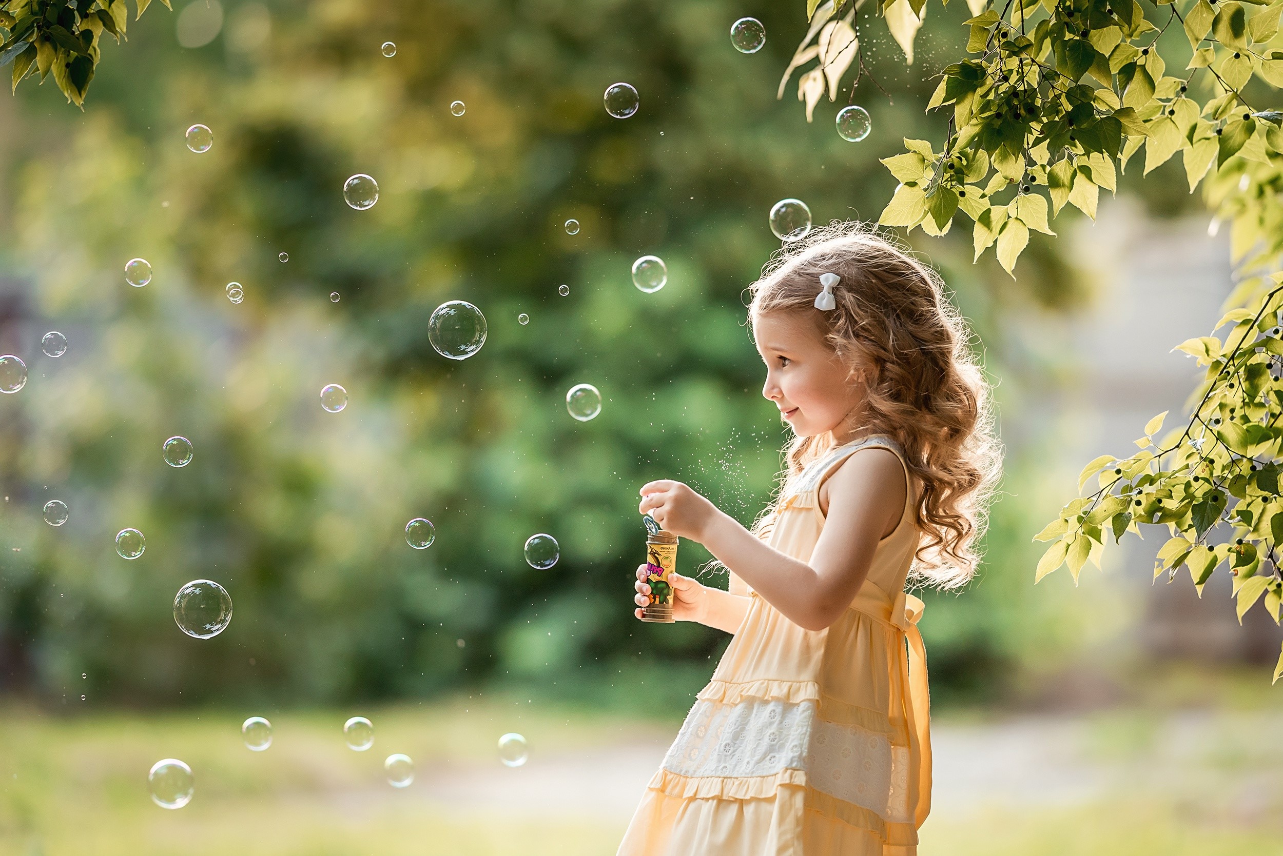 Little girl blowing soap bubbles outdoors HD Wallpaper