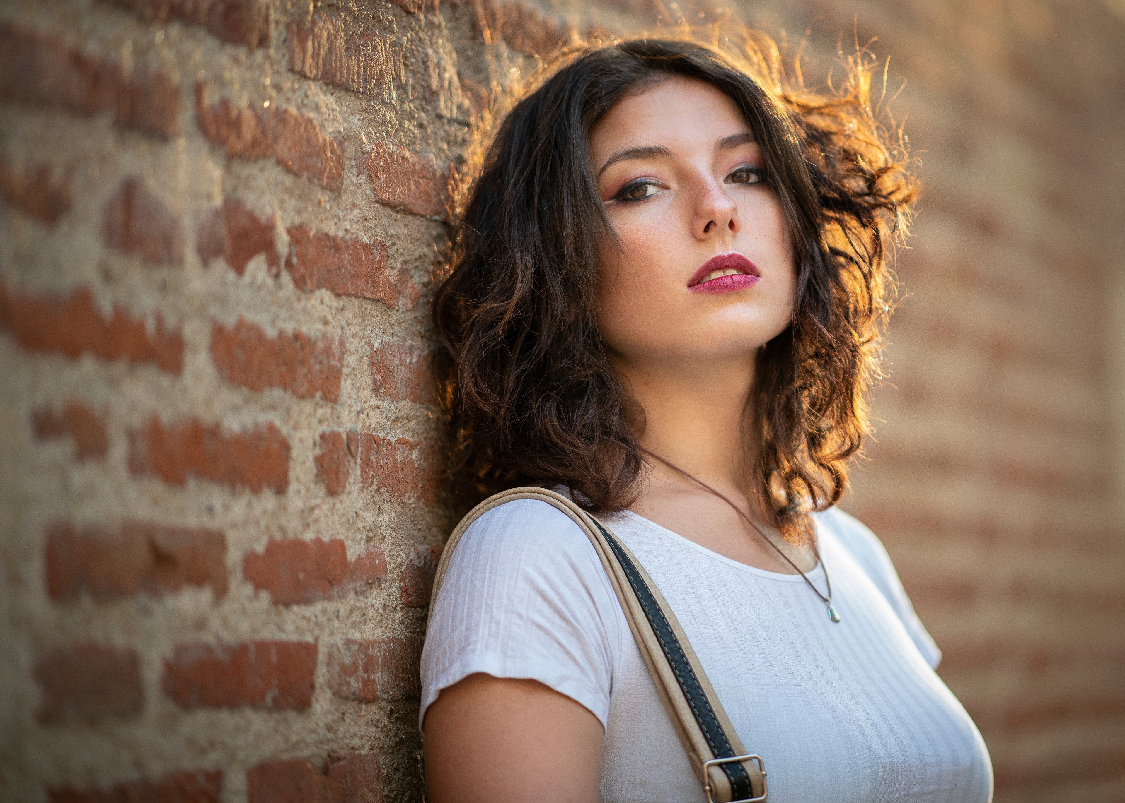 Woman with brown hair leaning against a brick wall HD Wallpaper