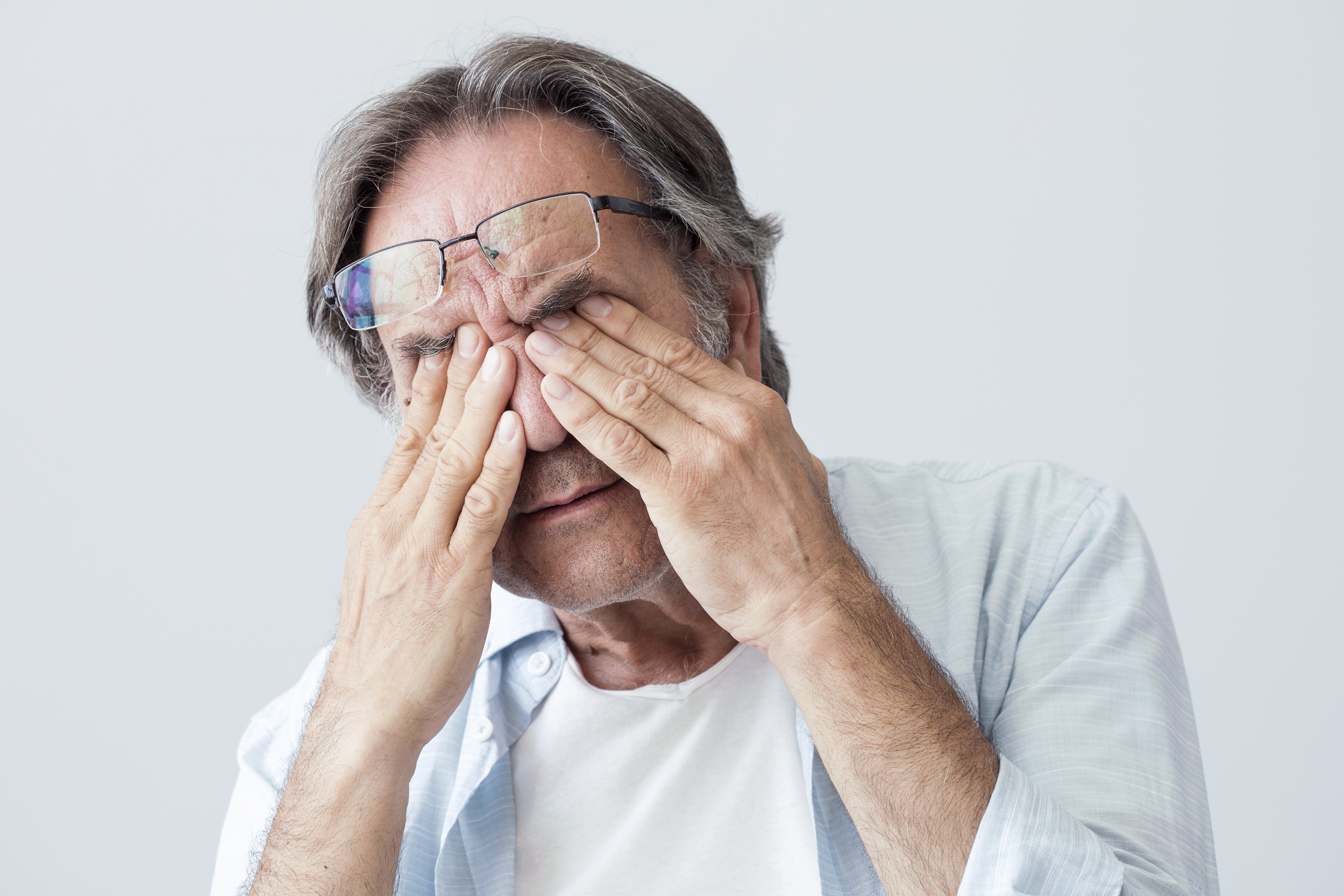Elderly man with glasses rubbing his eyes HD Wallpaper