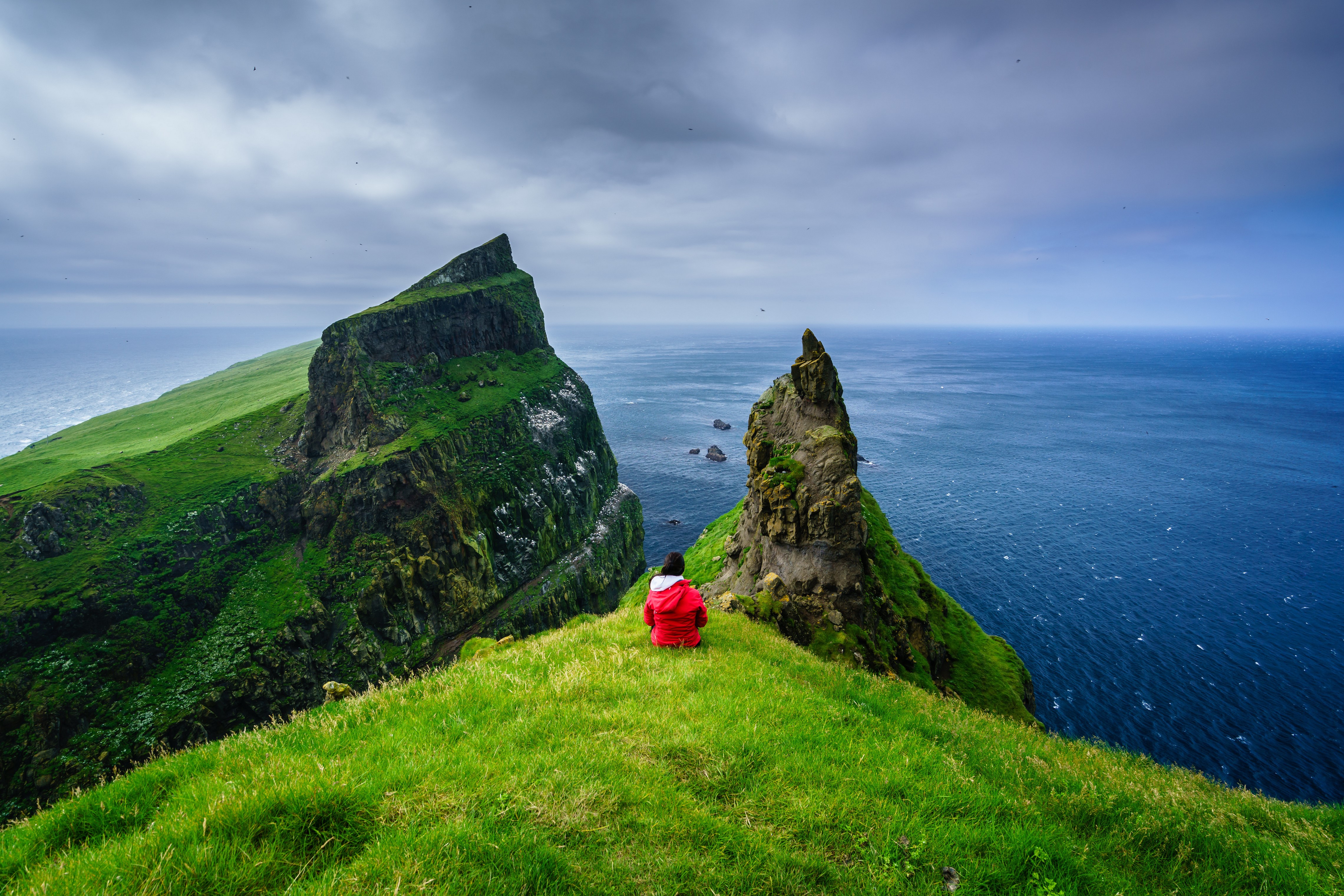 Person on cliff overlooking ocean in Faroe Islands HD Wallpaper