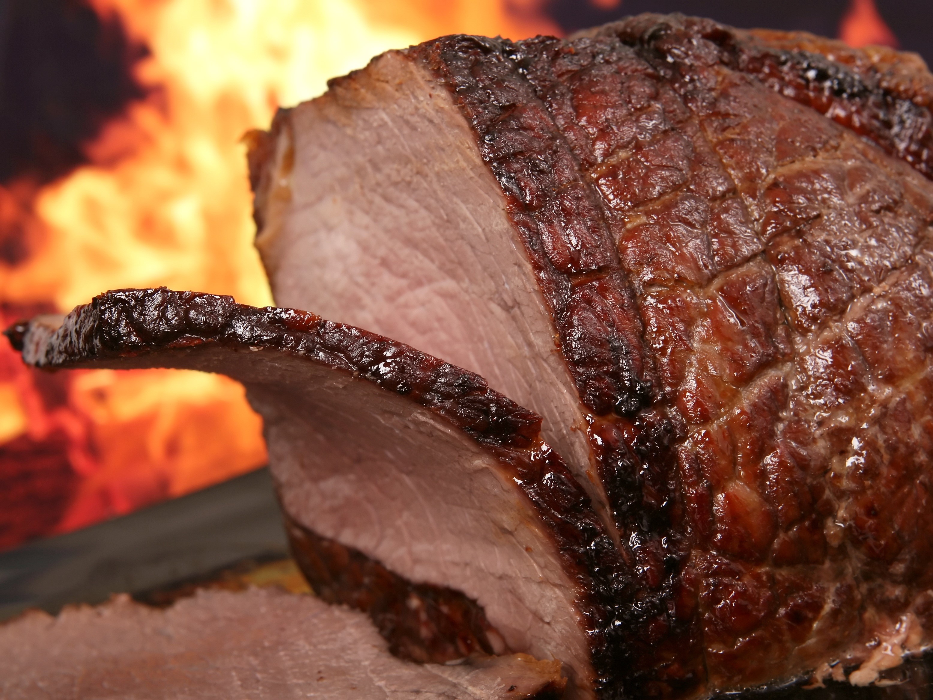Close-up of a roasted ham with flames in the background HD Wallpaper