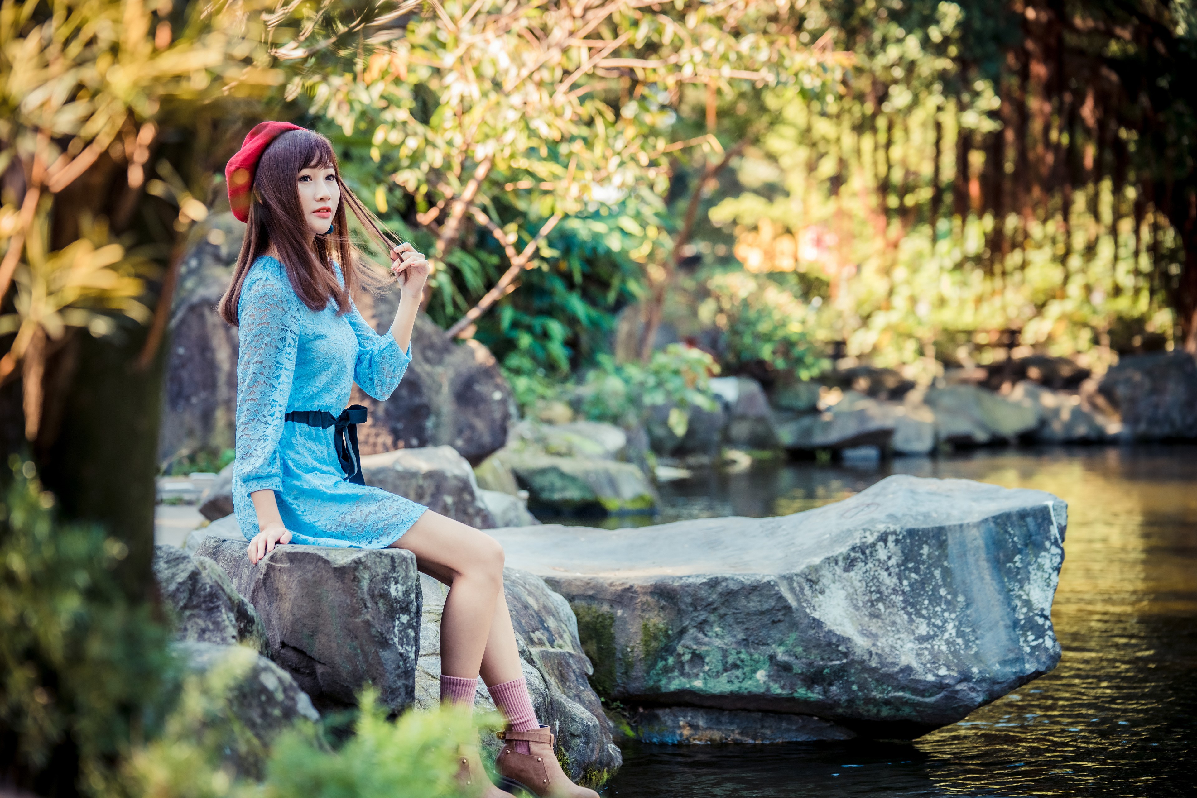 4K Asian Woman Sitting on Stones by Water HD Wallpaper