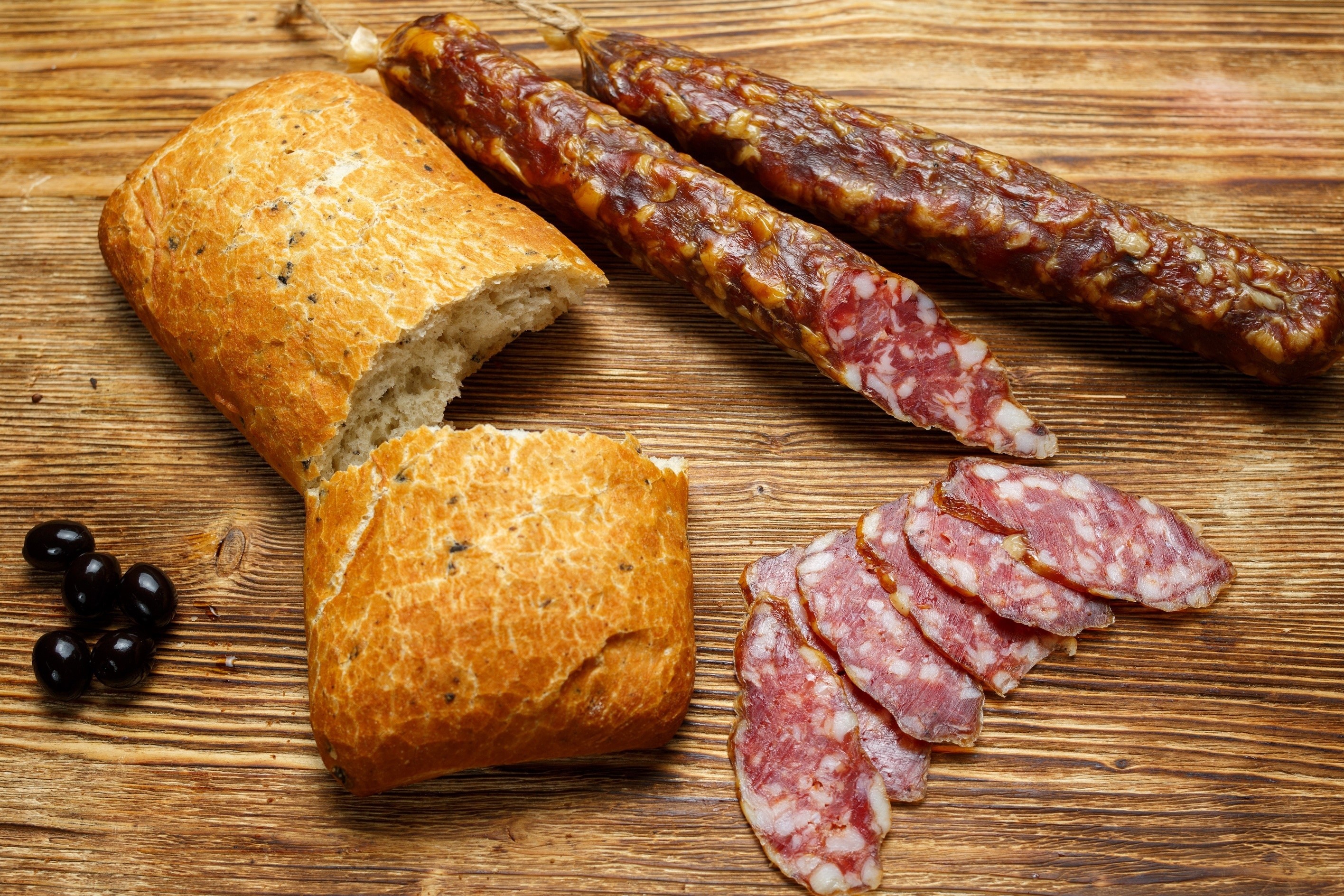 Bread, sausages, and olives on a wooden table HD Wallpaper