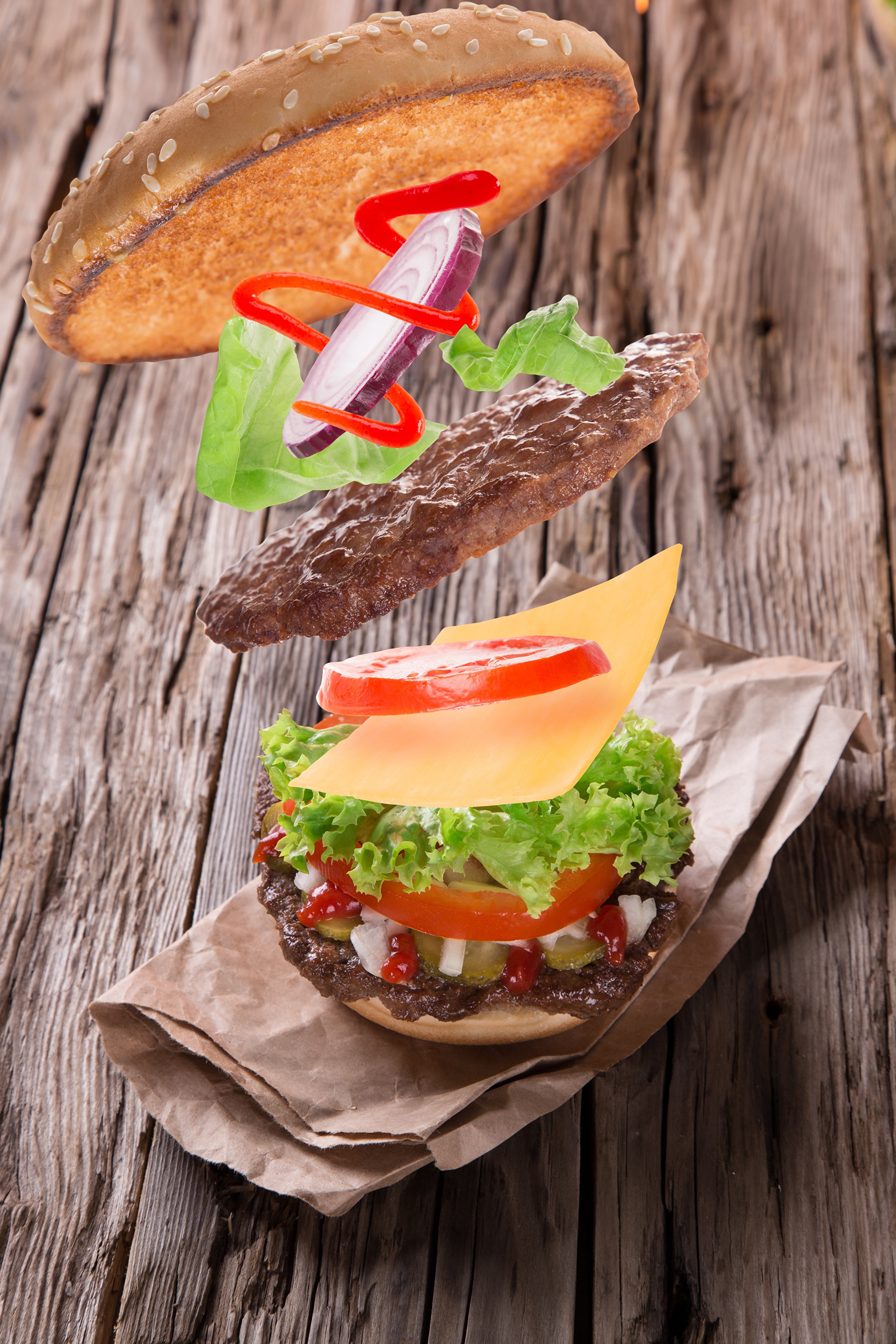 Deconstructed hamburger with flying ingredients on wood HD Phone Wallpaper