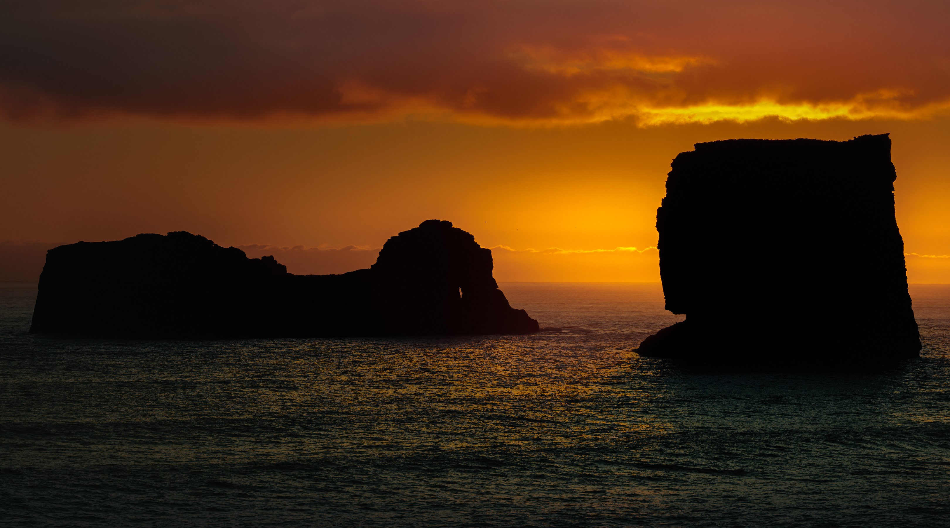 Silhouette of rock formations at Dyrholaey, Iceland during sunset HD Wallpaper