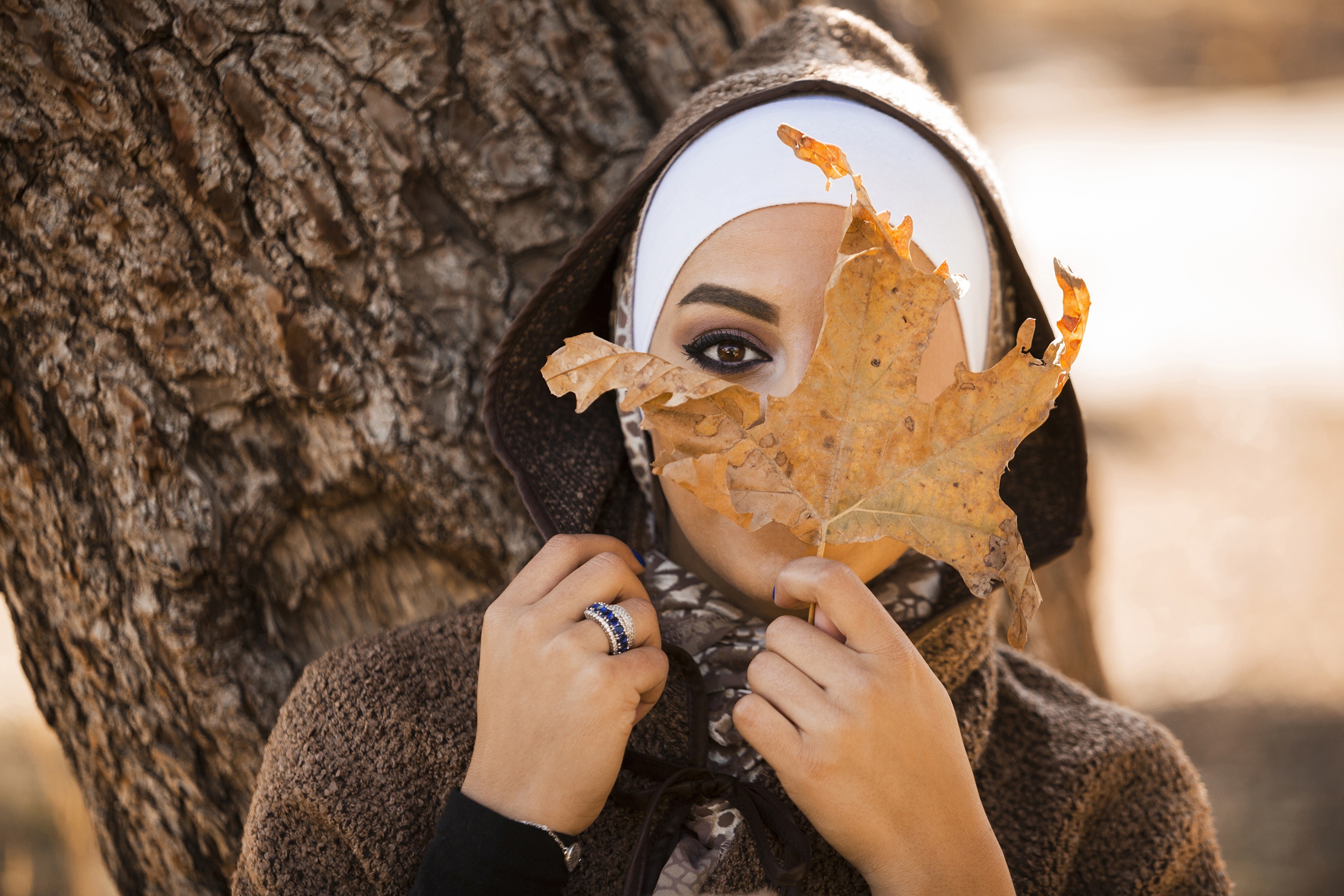 Woman in hijab holding a leaf in front of her face HD Wallpaper