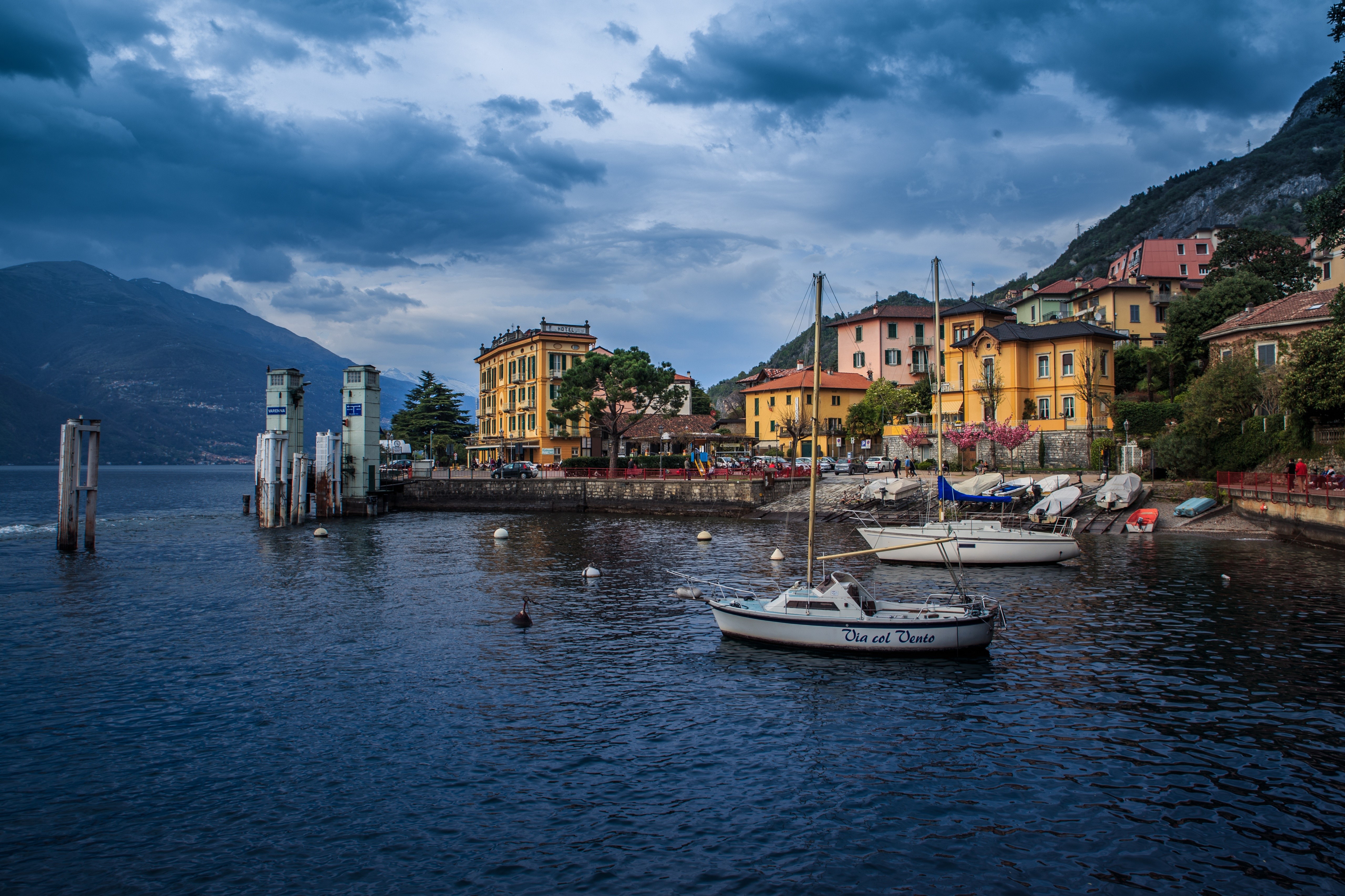 Boats docked in Varenna, Lombardy, Italy with mountains and clouds HD Wallpaper