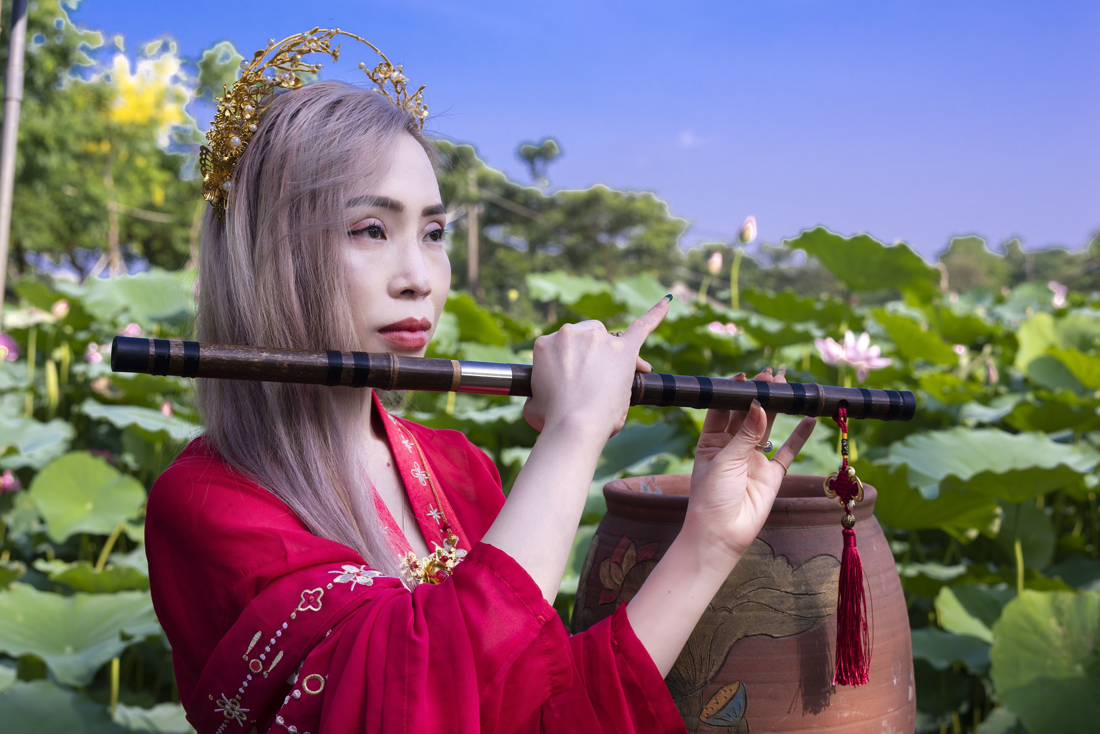 Woman playing flute in lotus pond HD Wallpaper