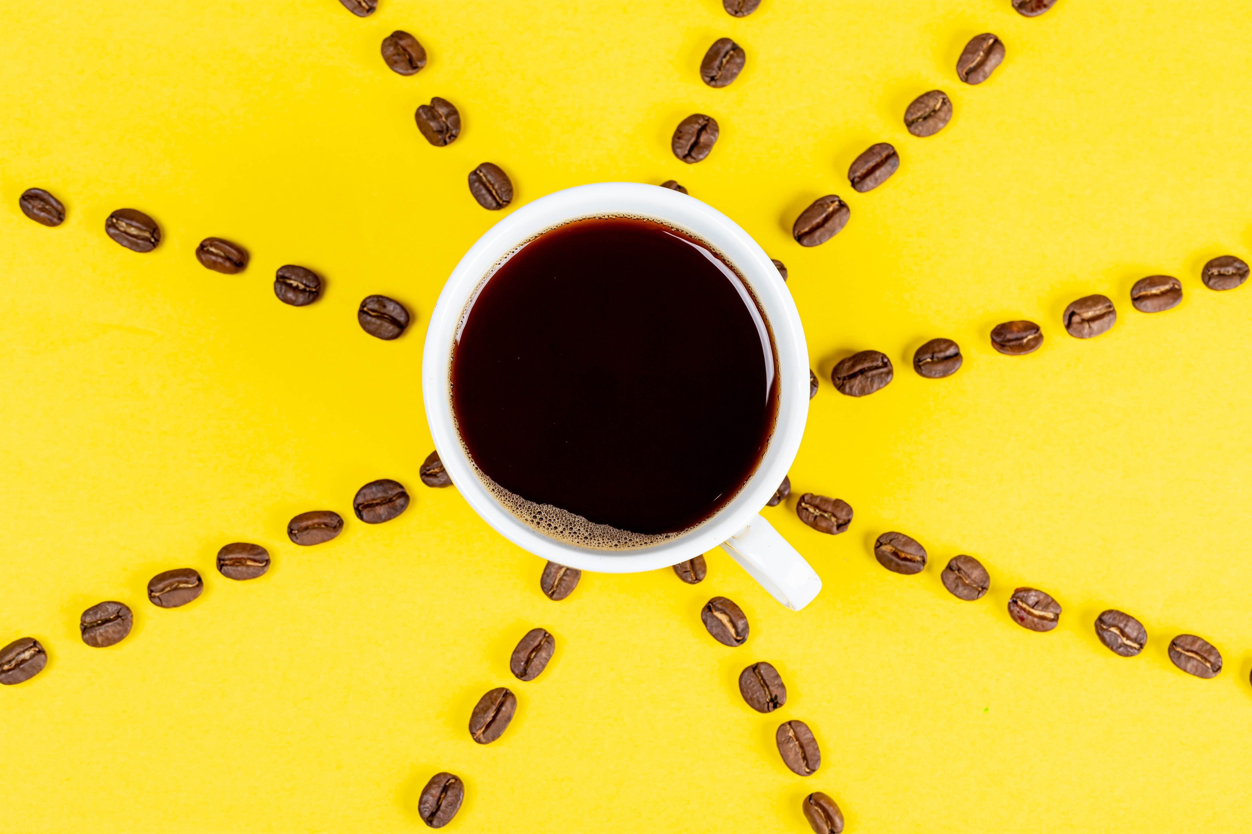 Coffee cup with coffee beans arranged like a sun HD Wallpaper