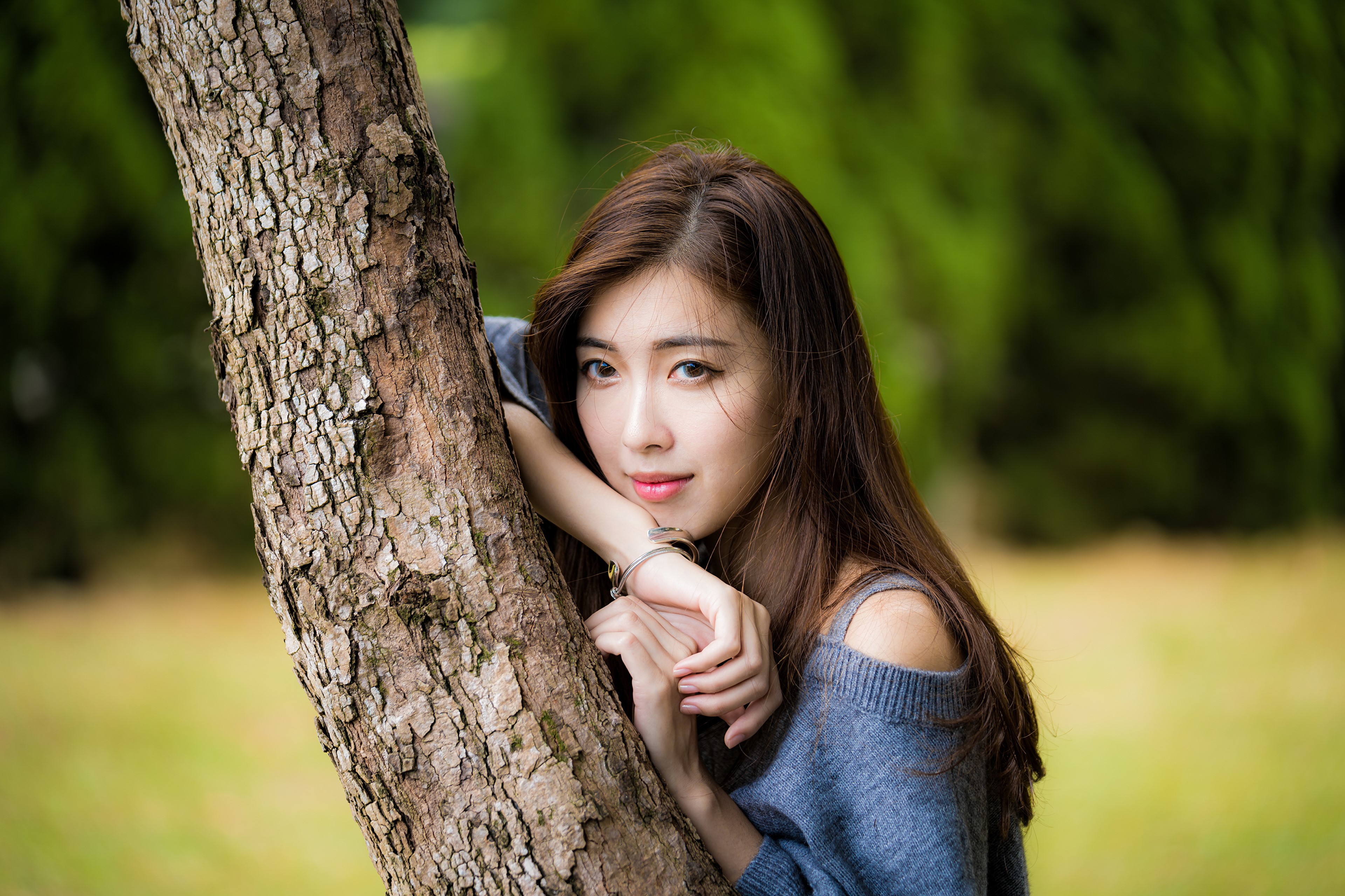 Asian woman with brown hair leaning on a tree trunk HD Wallpaper