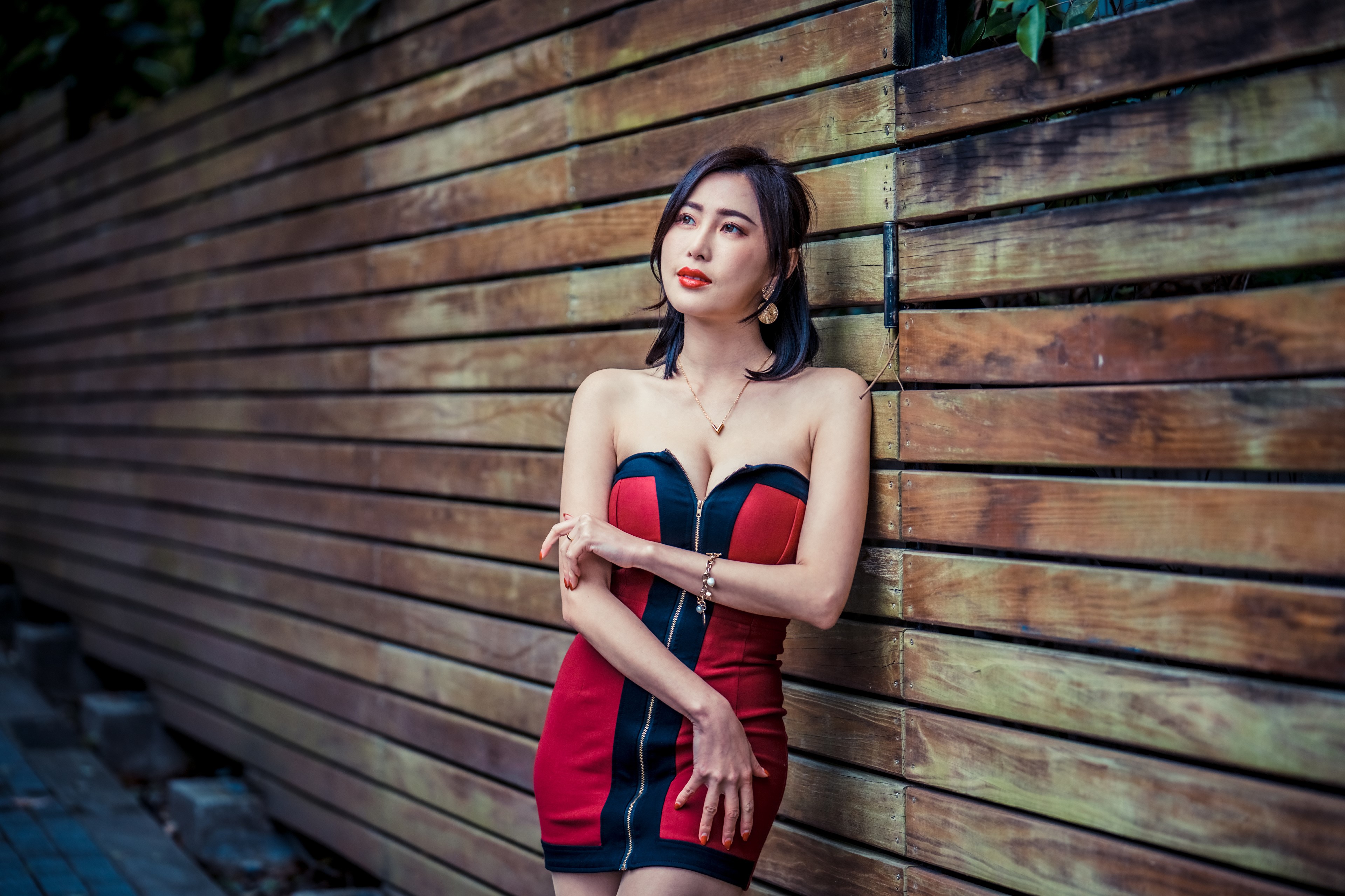 Asian woman in red and black dress leaning against wooden wall HD Wallpaper