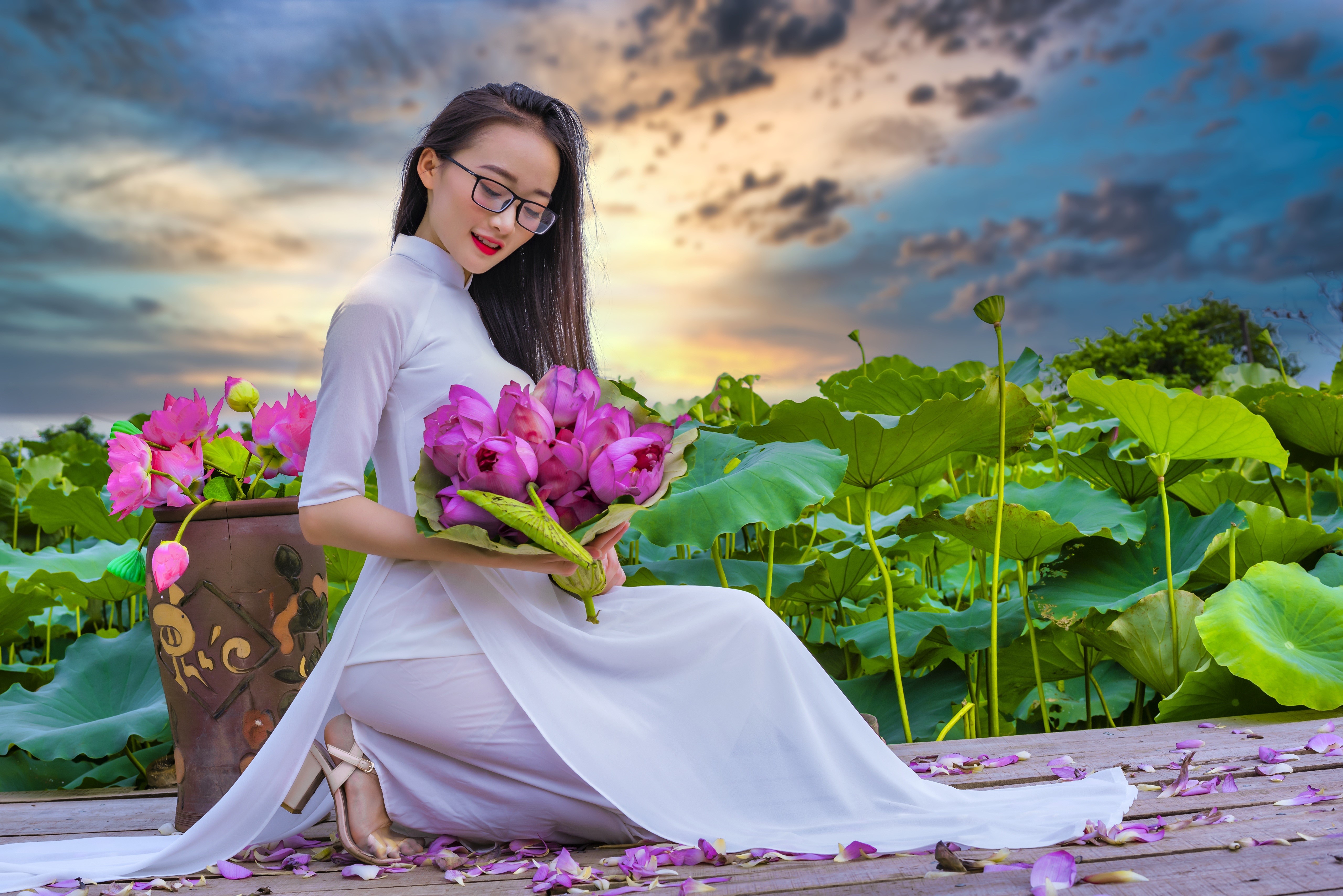 Woman in white dress holding lotus flowers in a lotus pond HD Wallpaper