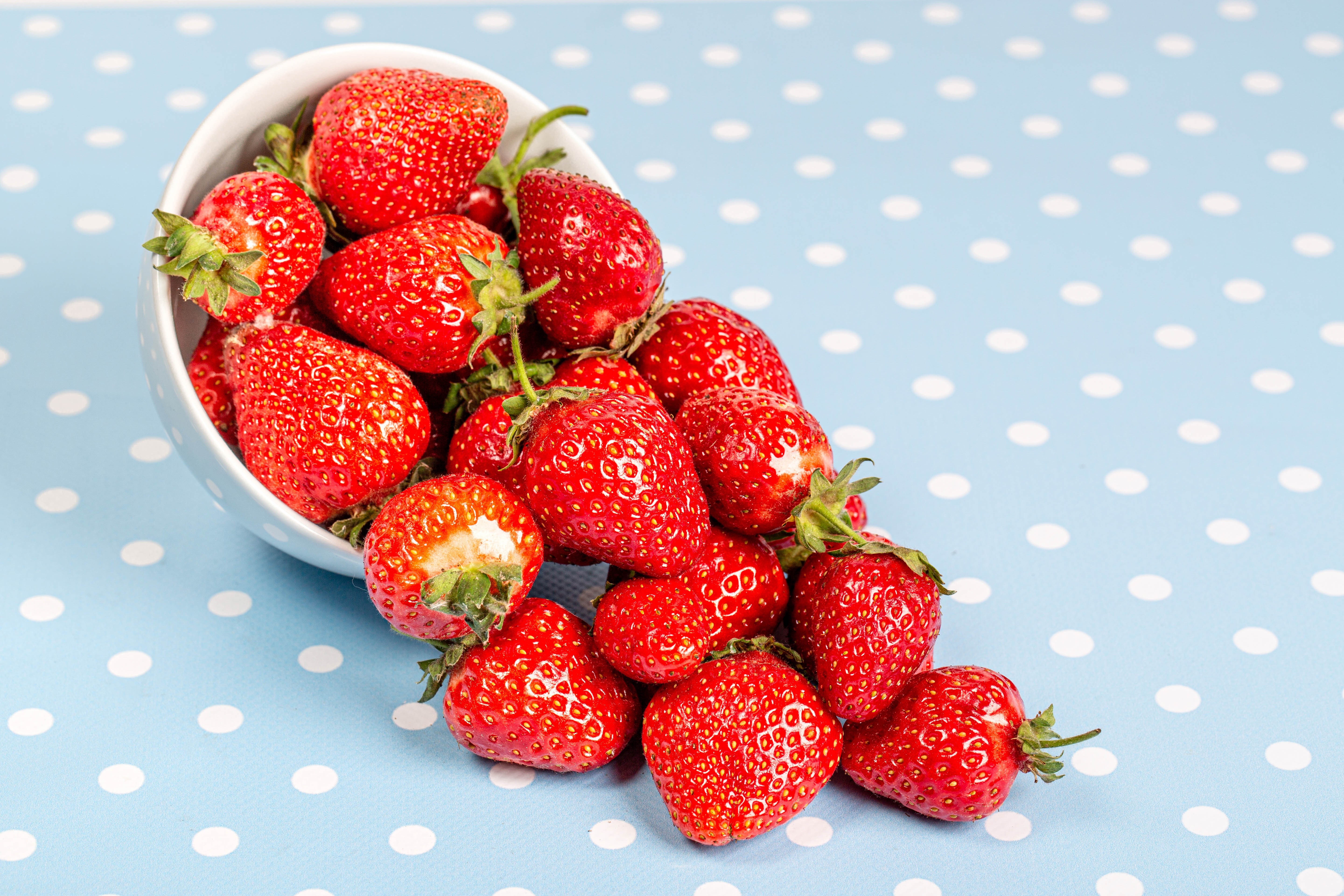 Strawberries spilling from a bowl HD Wallpaper