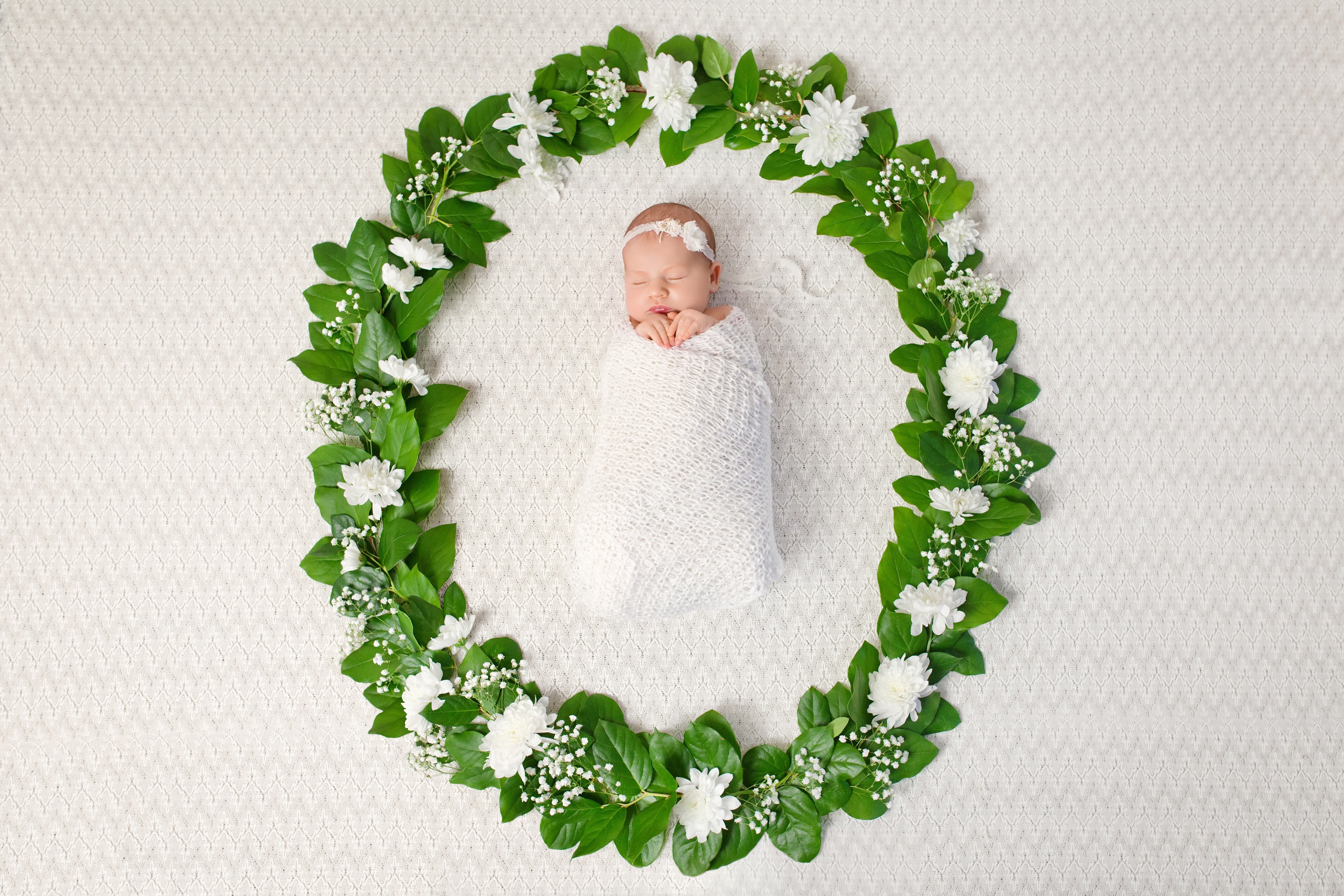 Newborn baby sleeping in a floral wreath HD Wallpaper