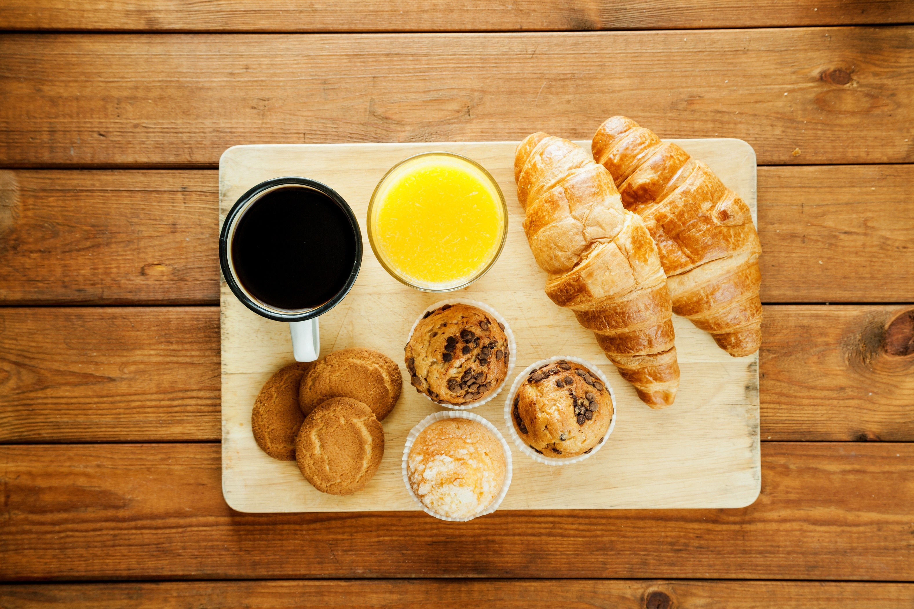 Breakfast tray with coffee, juice, croissants, muffins, and cookies HD Wallpaper